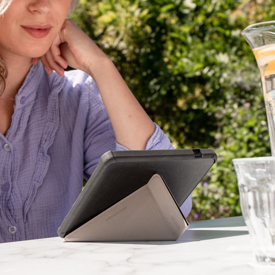 Vrouw die een tablet gebruikt op een tafel buiten. Tablet staat in een standaard.