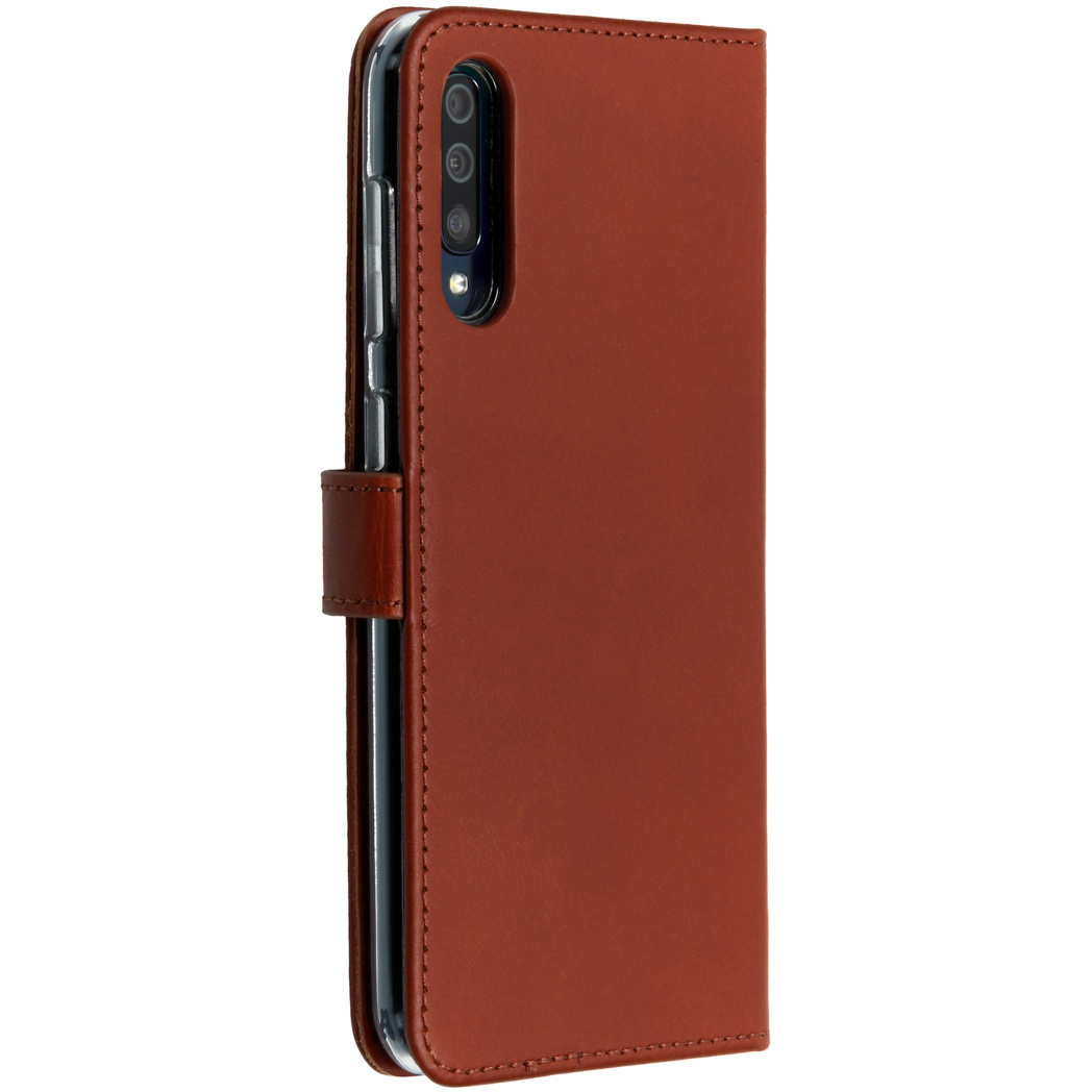Een telefoon in een bruine leren hoes, gesloten. De hoes is bruin. De camera van de telefoon is zichtbaar.