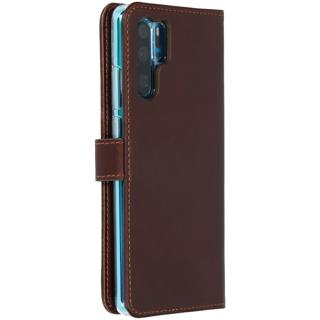 Un étui de téléphone en cuir marron, fermé, avec le téléphone à droite, montrant caméra et boutons.