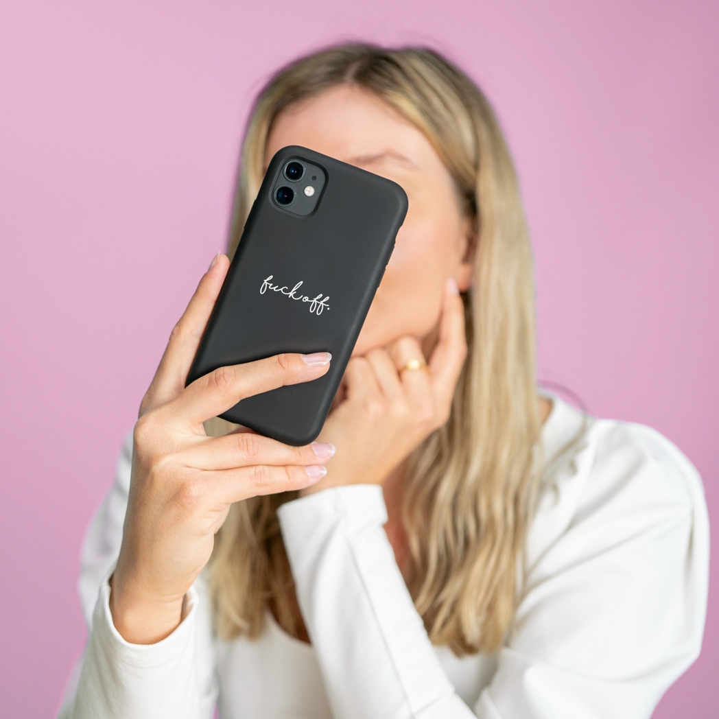 Femme tenant un téléphone avec l'inscription "fuck off".