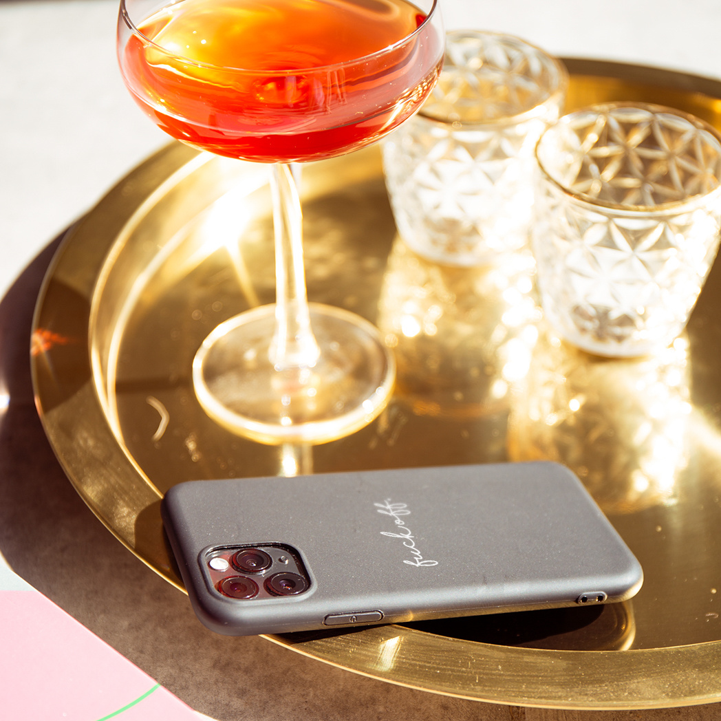 Gouden dienblad met drankje, twee glazen en een telefoonhoesje met 'fuck off'.
