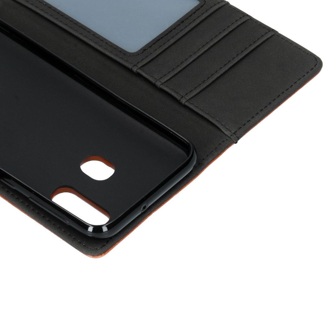 Telefoonhoesje met de telefoon erin. De hoes is zwart en bruin. Het telefoonhoesje is open.