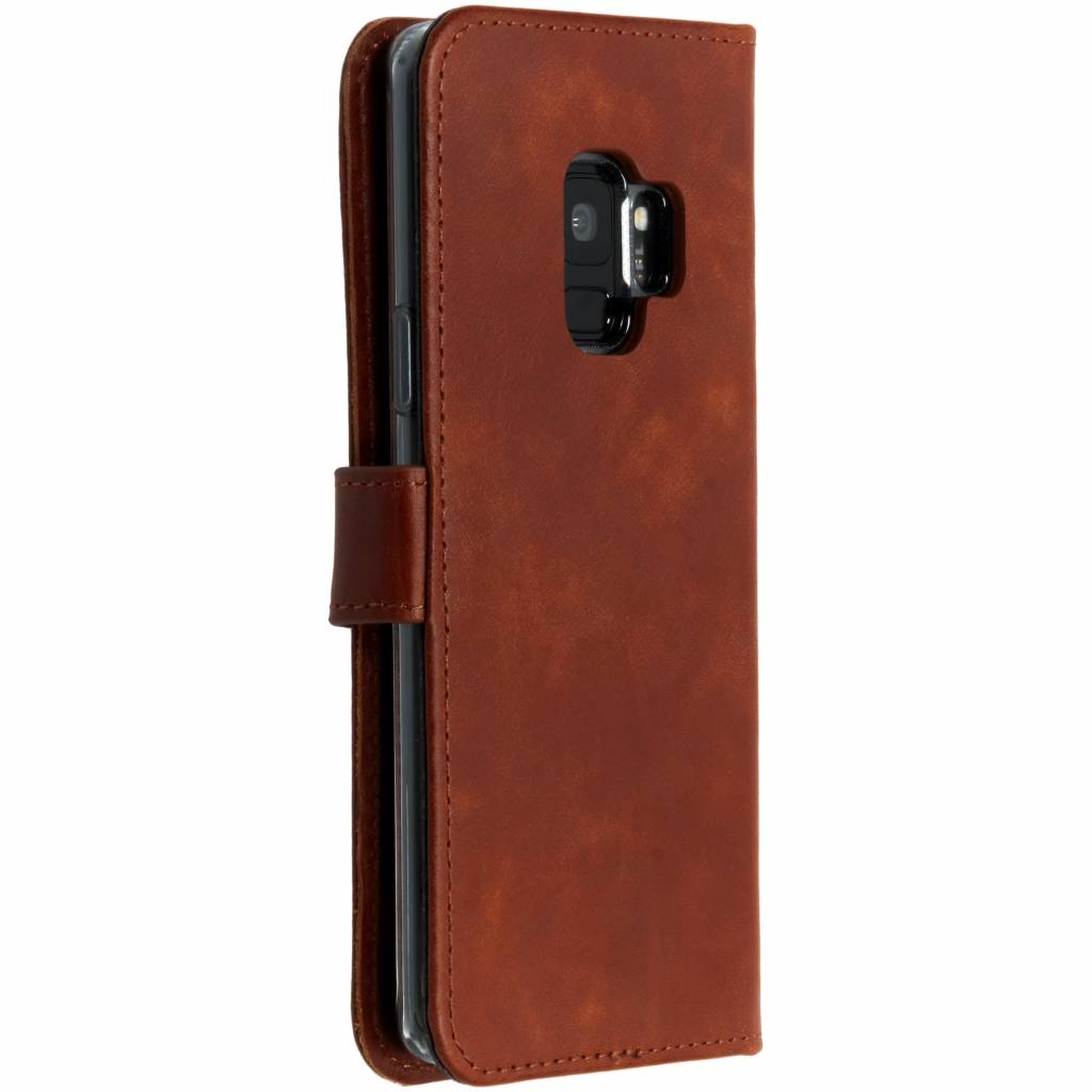 Bruine leren telefoonhoes in portemonnee-stijl, gesloten. Toont de camera en telefoon.