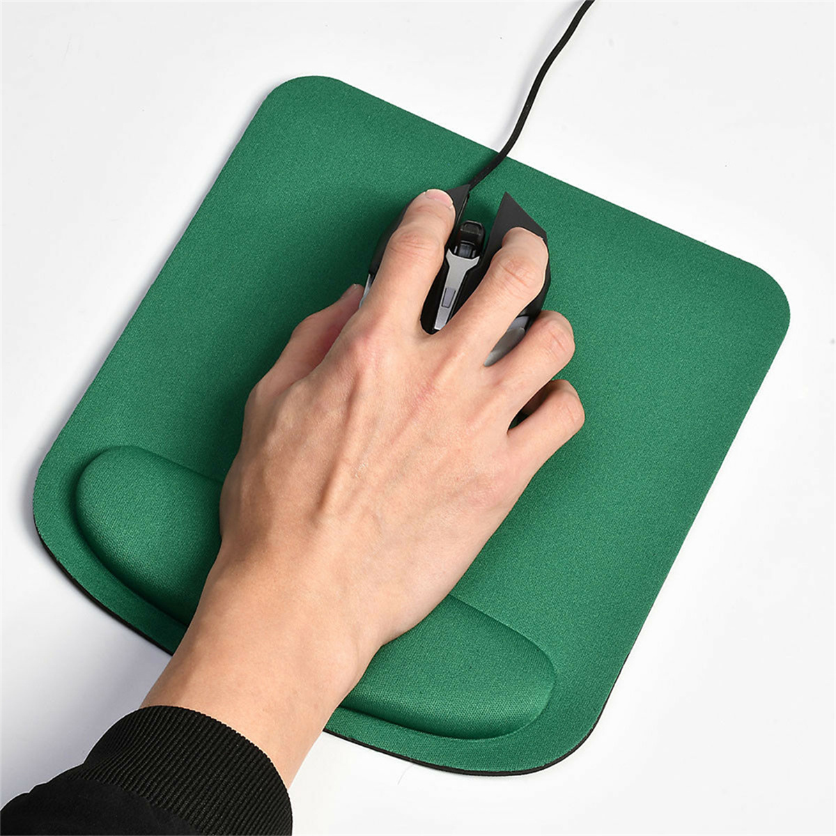 Hand mit Maus auf grünem Mauspads mit Handgelenkstütze. Schwarze Maus und weißer Hintergrund.