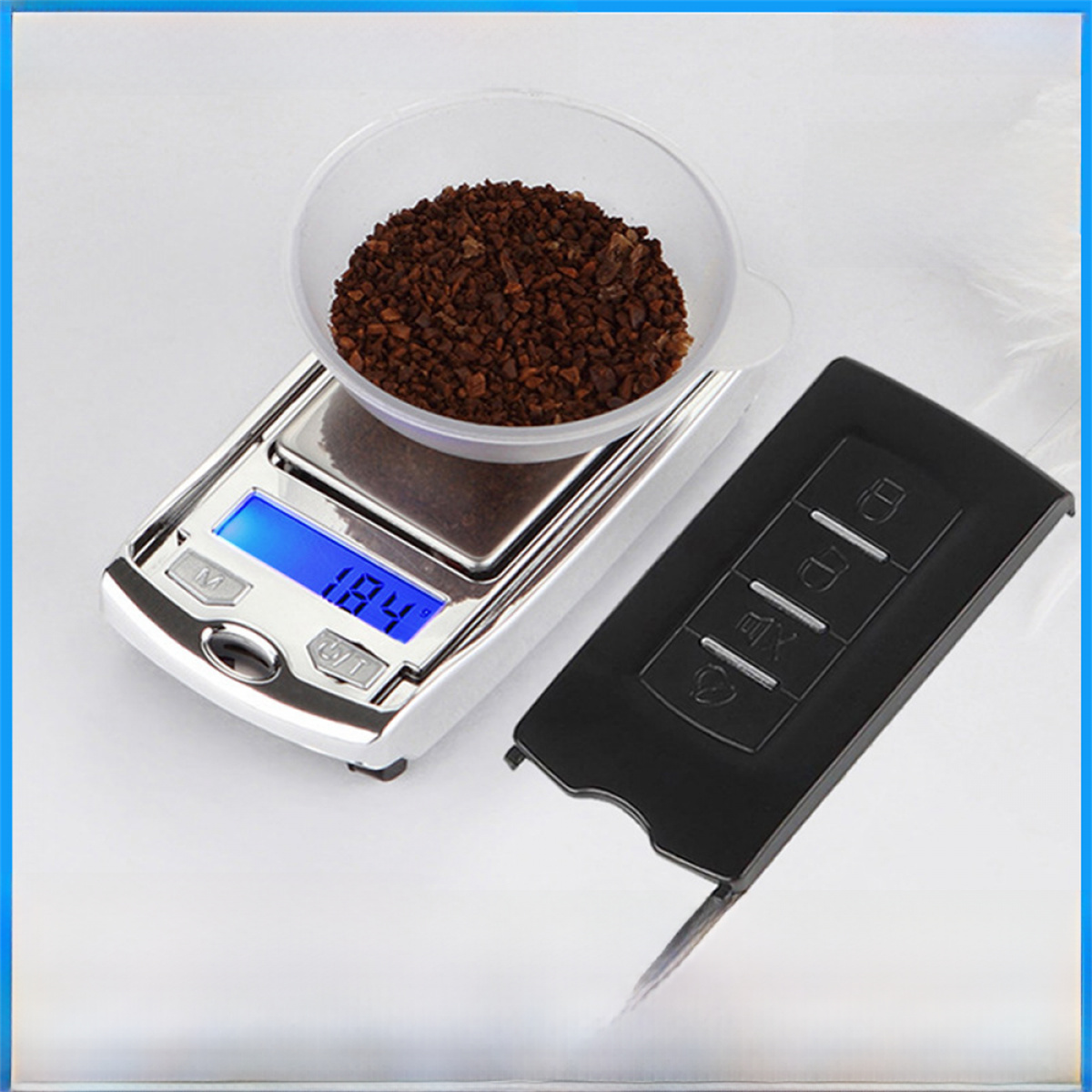 Eine Kaffeewaage und ein Autoschlüssel. Die Waage hat Kaffeepulver in einer Schüssel.