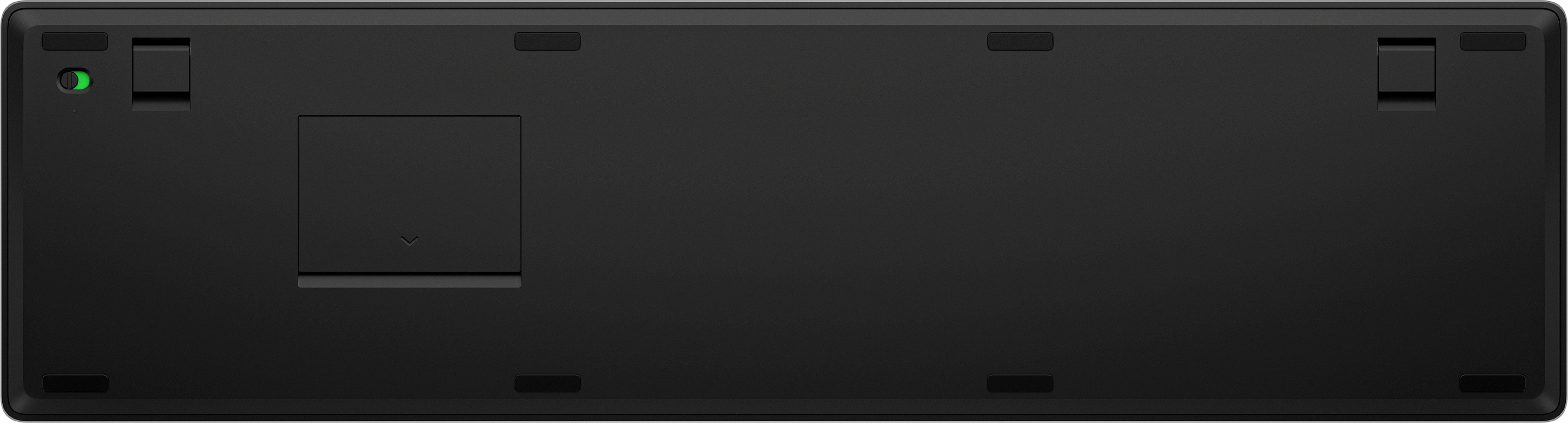 Widok od spodu czarnej klawiatury z małymi prostokątnymi nóżkami i komorą baterii.