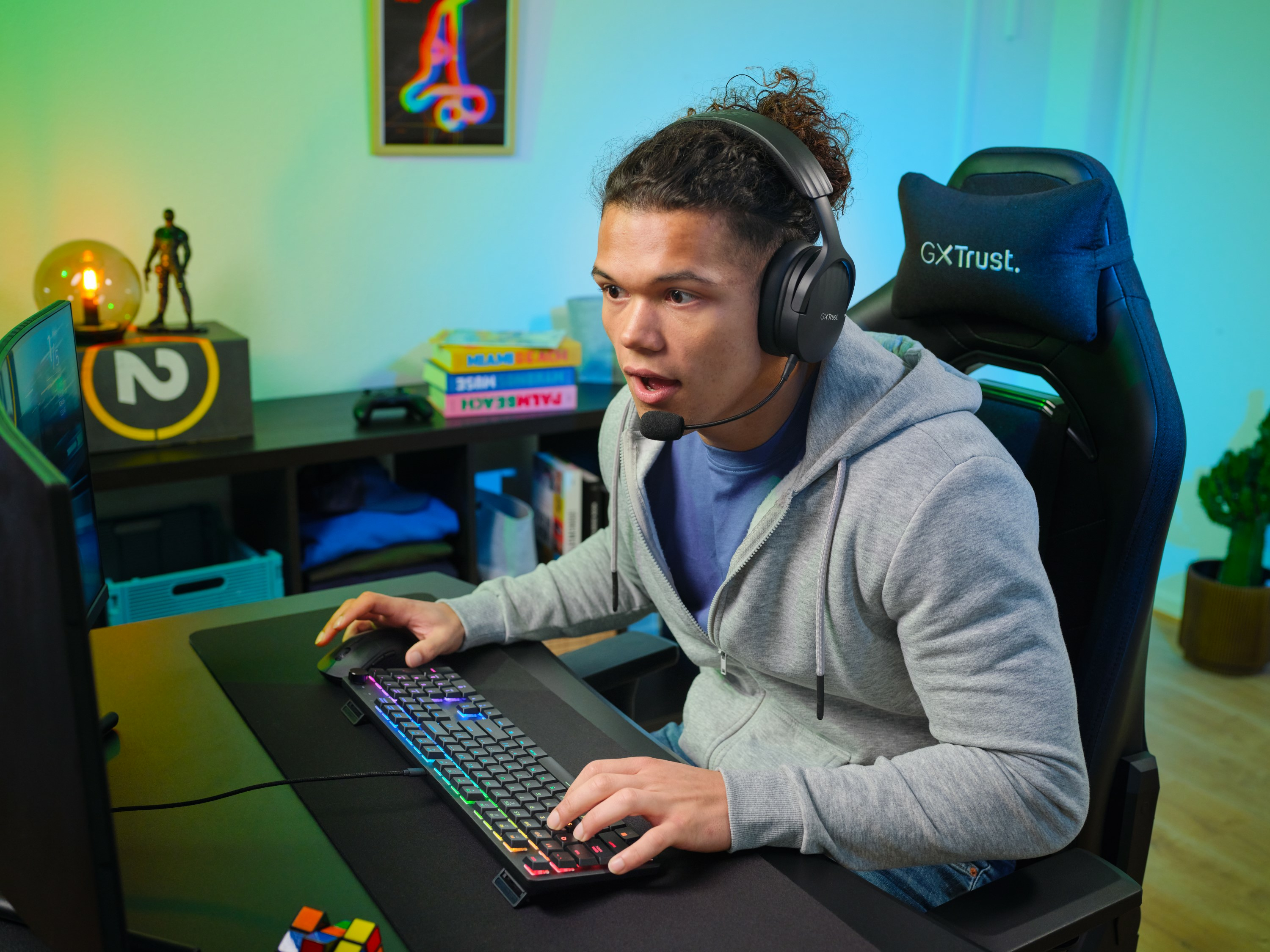 Junger Mann spielt mit Kopfhörern, Tastatur mit RGB-Lichtern, überraschter Ausdruck.