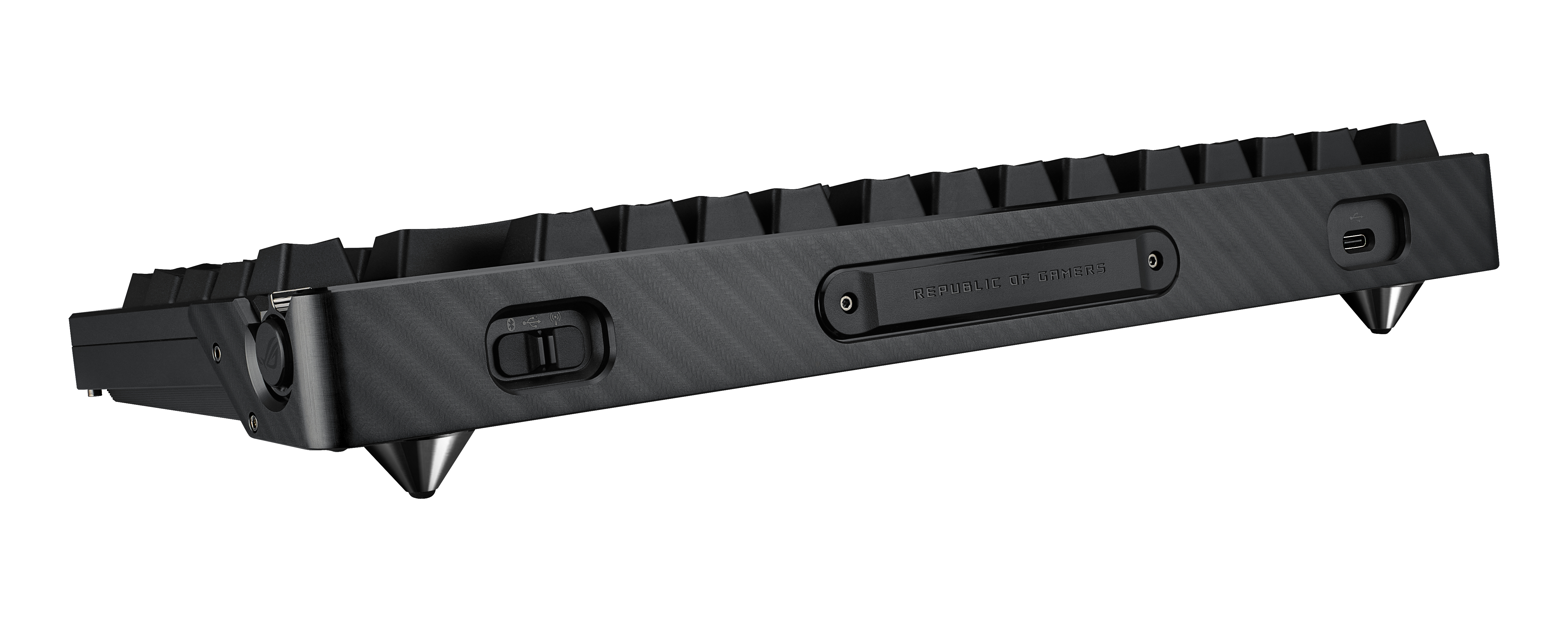 Czarna klawiatura z boku, z ciemną, teksturowaną powierzchnią. Posiada złącza i nóżki.