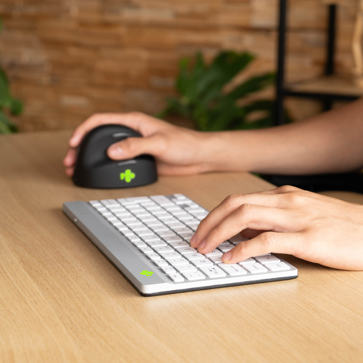 Mani che usano una tastiera e un mouse su una scrivania di legno.