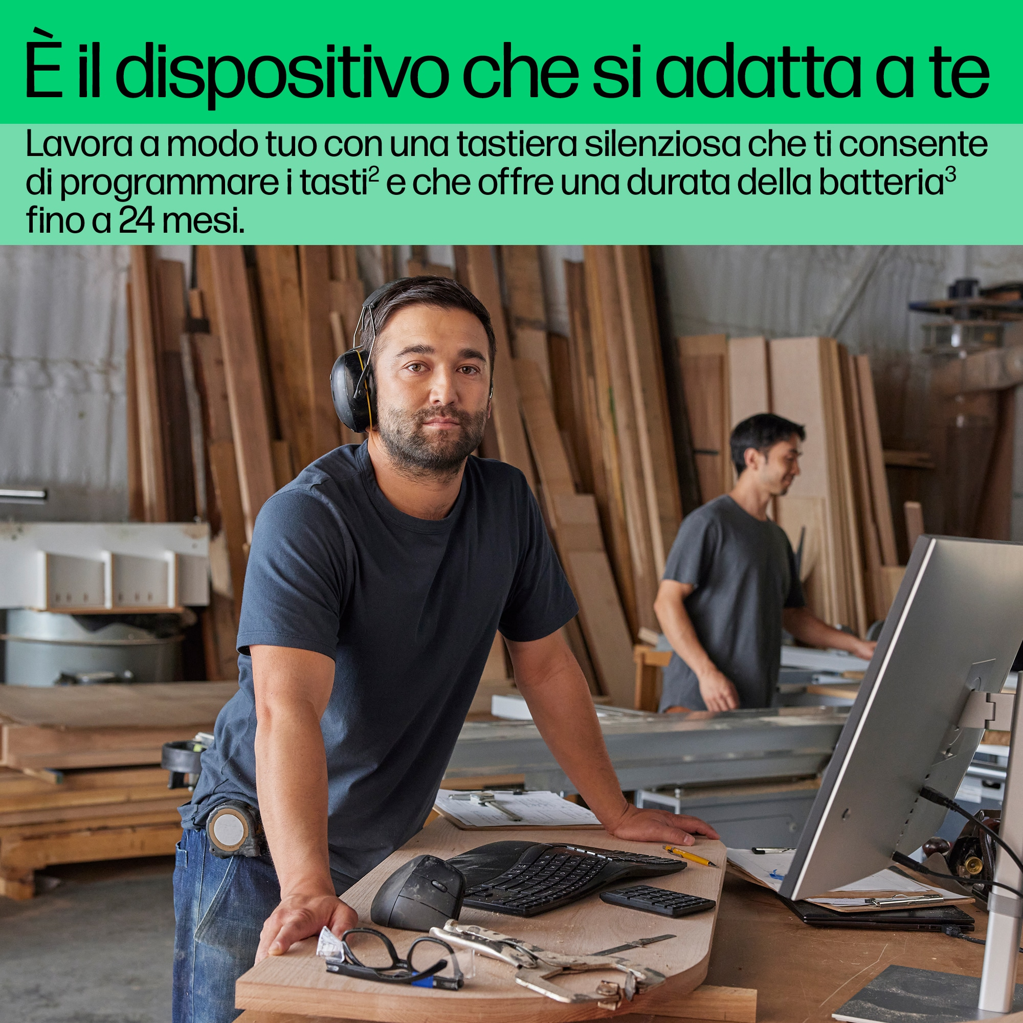 Uomo usa tastiera e mouse, in officina, con monitor.
