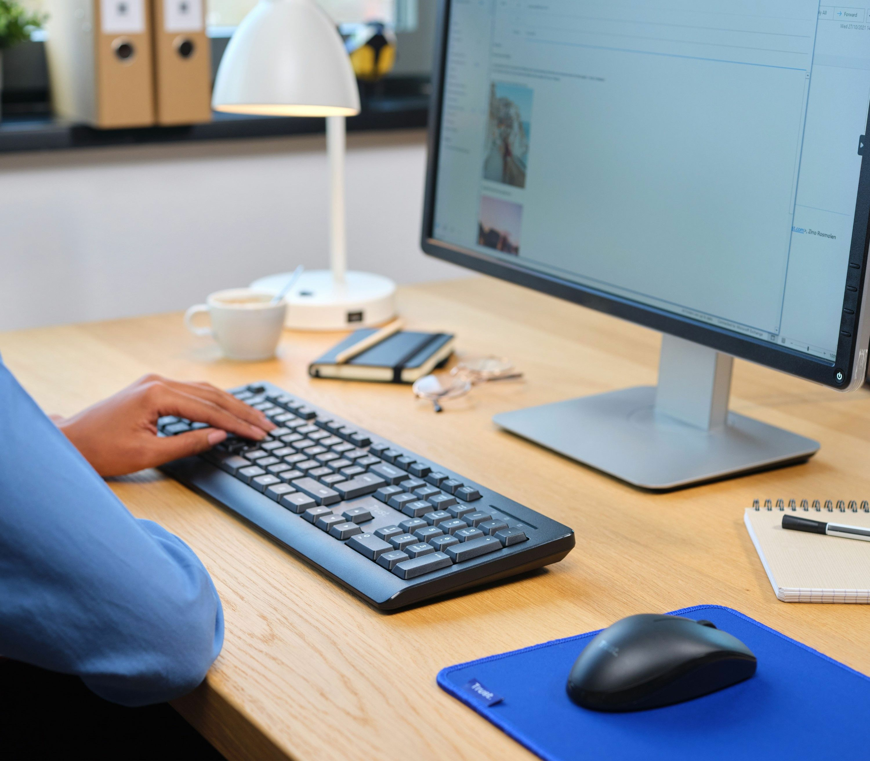 Ręce piszące na czarnej klawiaturze, ustawienie biurka.