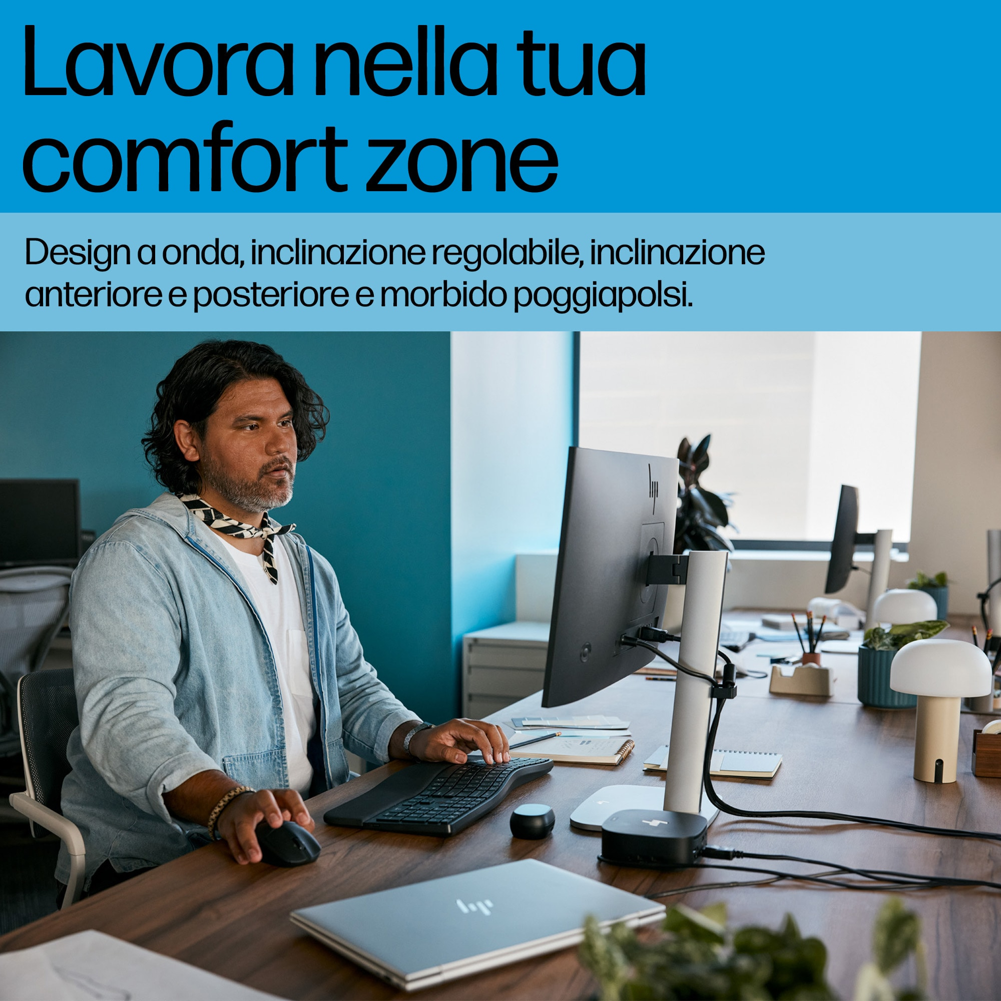Uomo che lavora su un computer con tastiera e mouse. È seduto a una scrivania di legno con un monitor.