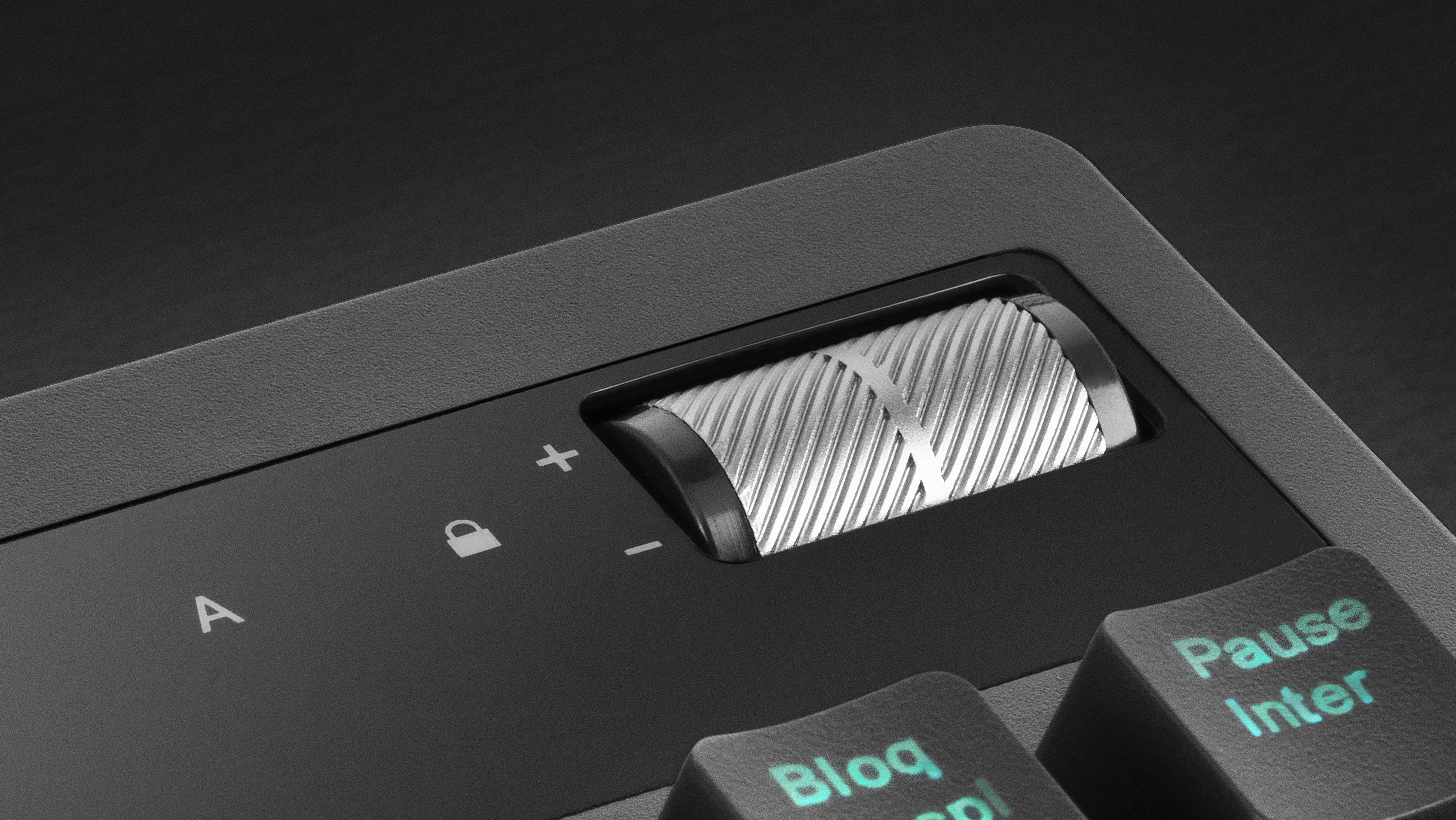 Nahaufnahme eines Drehreglers auf einer Tastatur, mit Plus- und Minuszeichen.