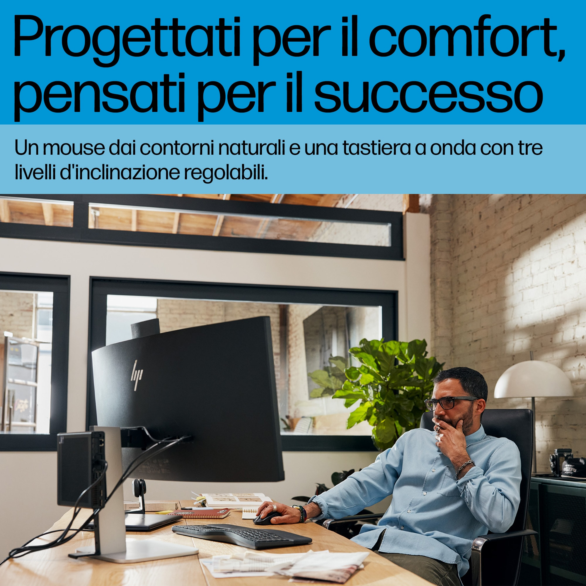 Uomo seduto a una scrivania con monitor e tastiera. Il testo in alto è in italiano.