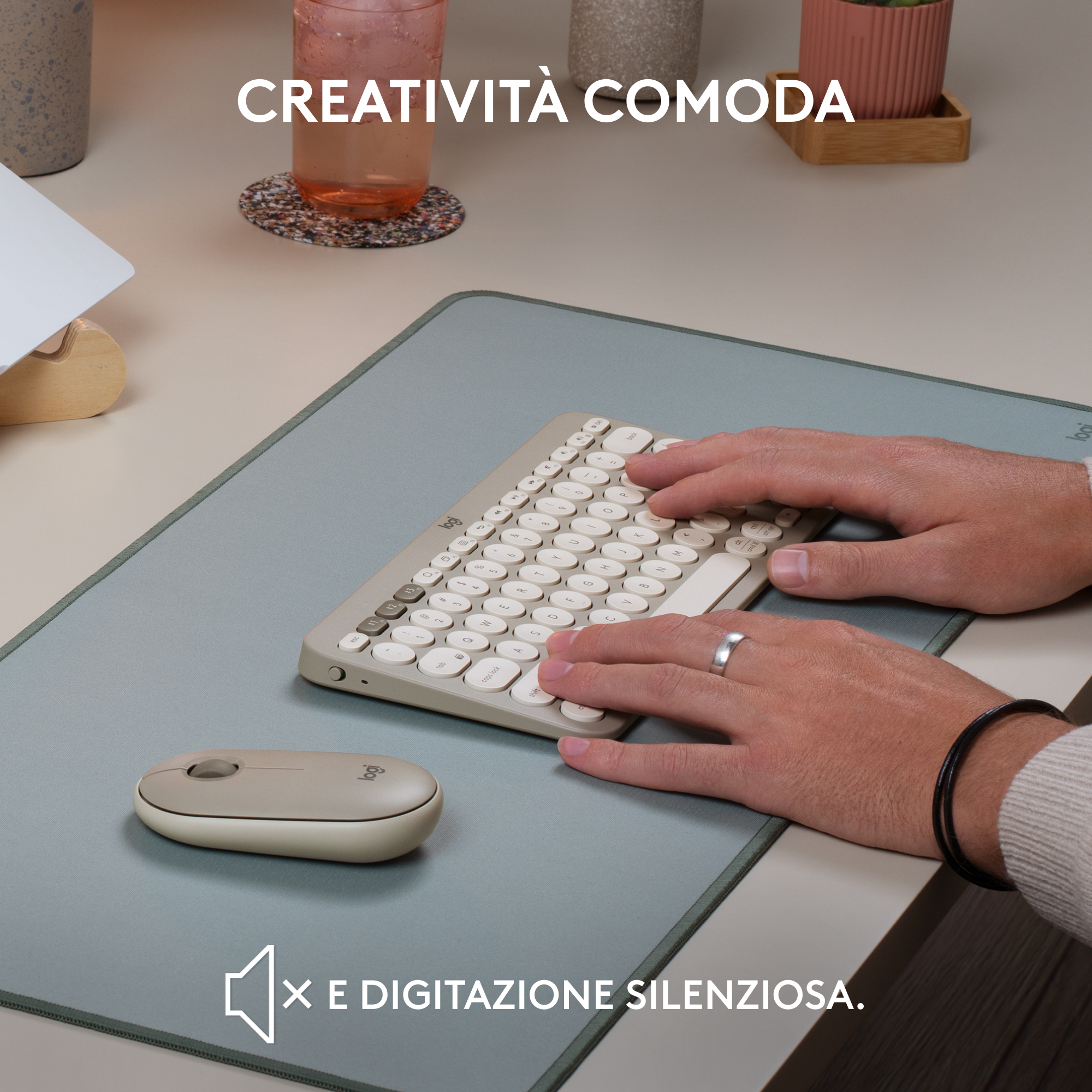 Mani che digitano su una tastiera beige e usano un mouse beige. La scena è ambientata su un tappetino grigio.