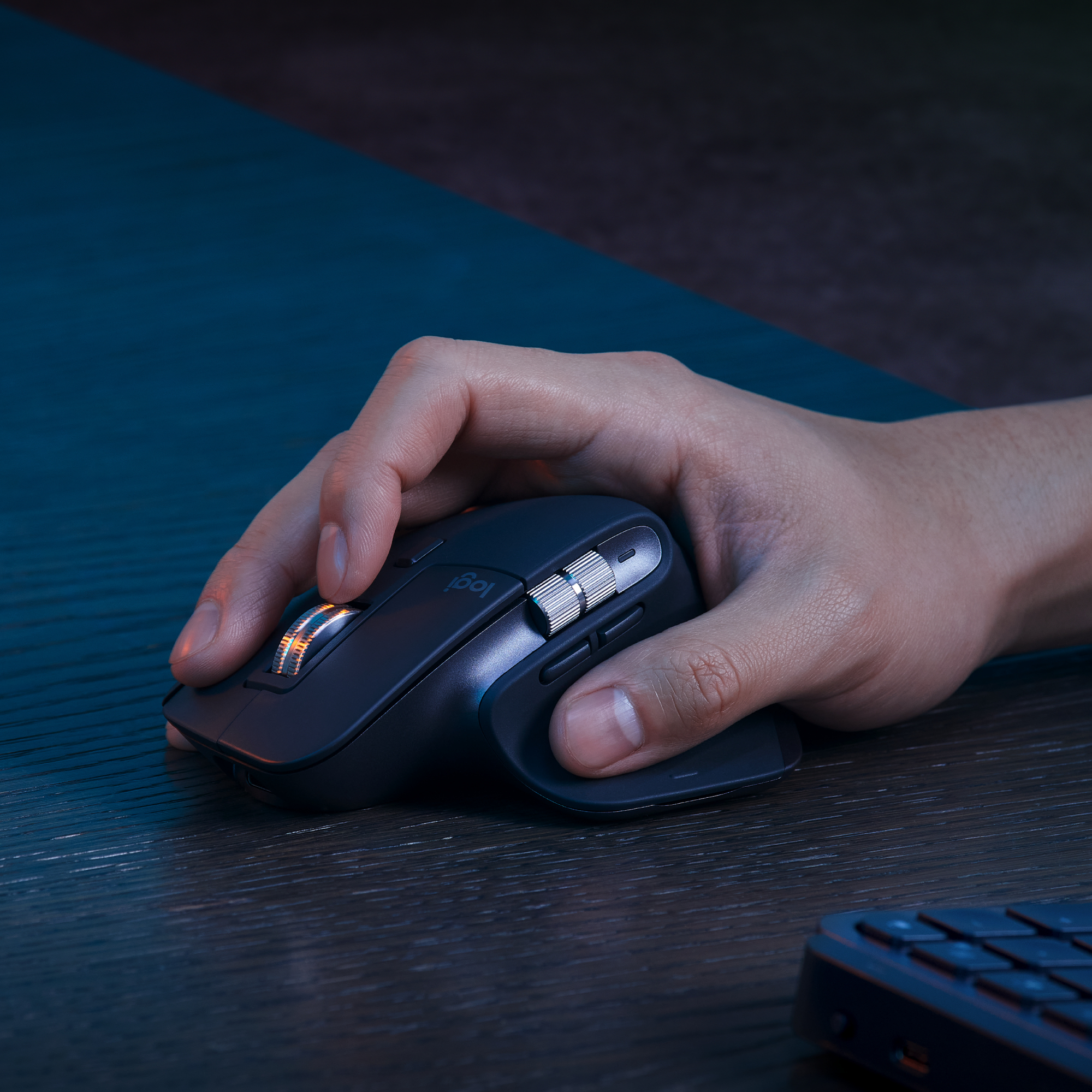 Mano usa un mouse scuro su una scrivania di legno. Il mouse ha dettagli argento.