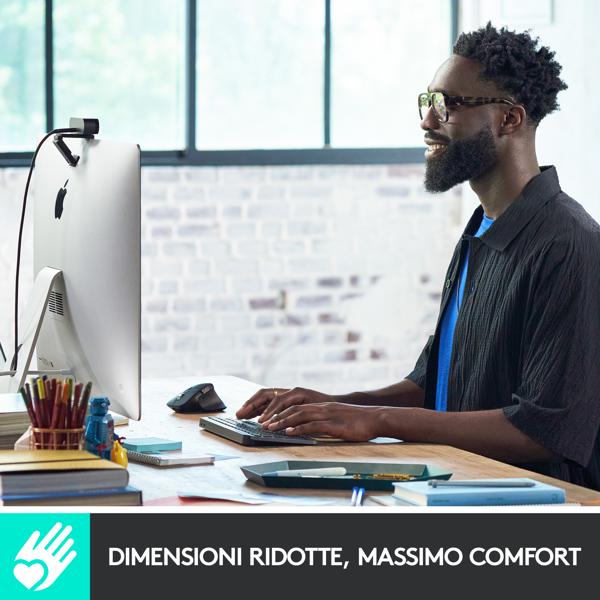 Mężczyzna w okularach korzystający z komputera z klawiaturą i myszą, uśmiechnięty.