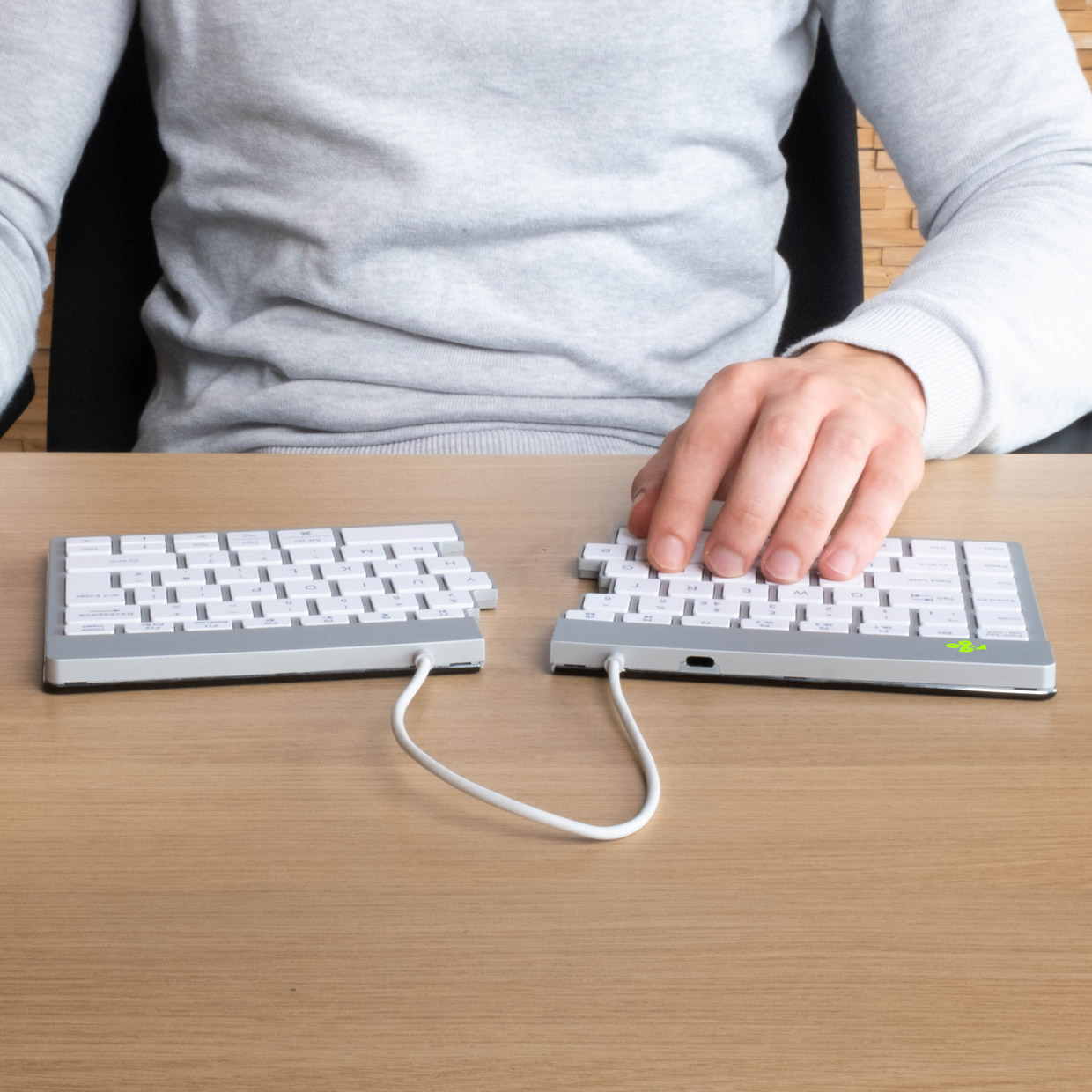 Hände auf einer geteilten Tastatur. Eine Hand links, die andere rechts.