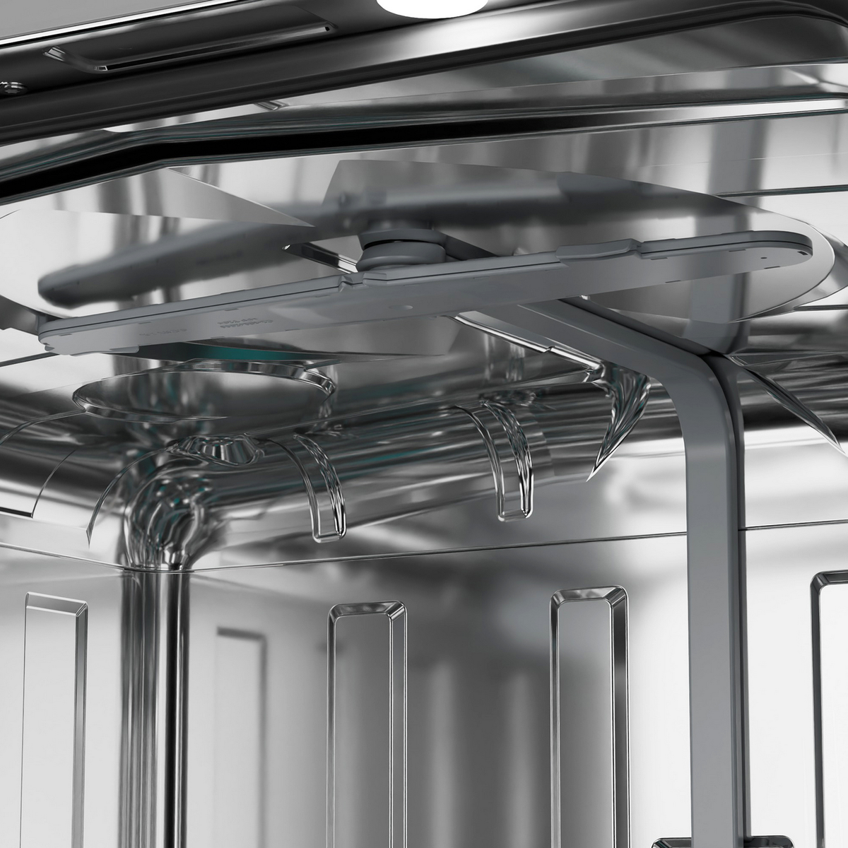 Wewnątrz zmywarki. Góra jest błyszcząca. Widoczne są ramiona natryskowe i stojaki. Srebrny metal.