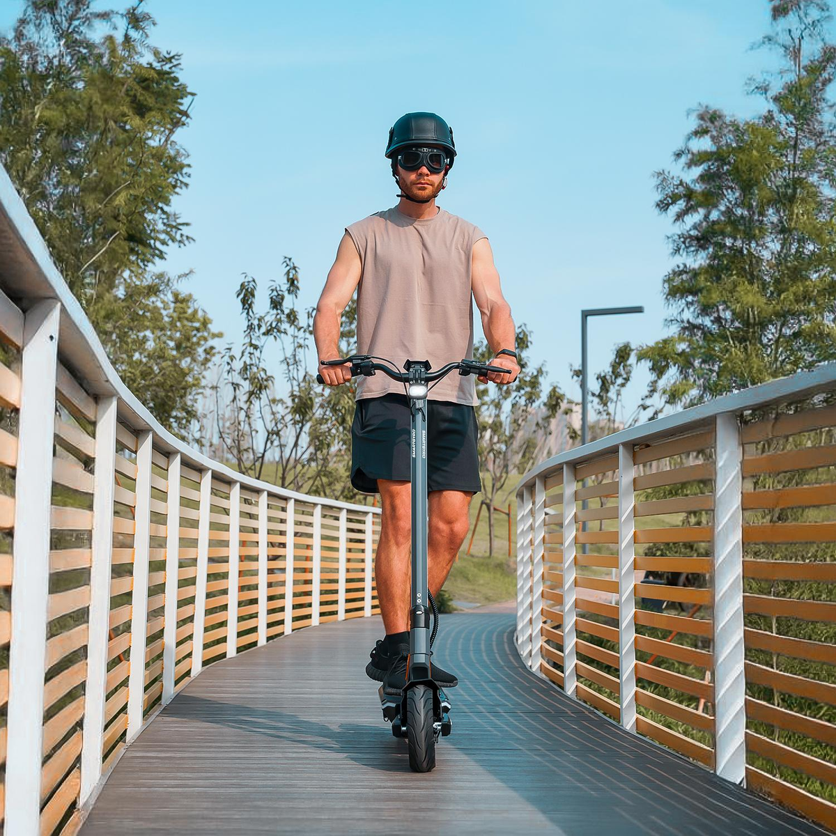 Un hombre con casco conduce un patinete eléctrico en un puente.