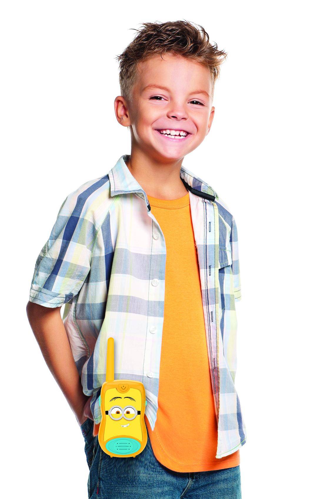 Garçon souriant, tenant un talkie-walkie Minion. Fond blanc.