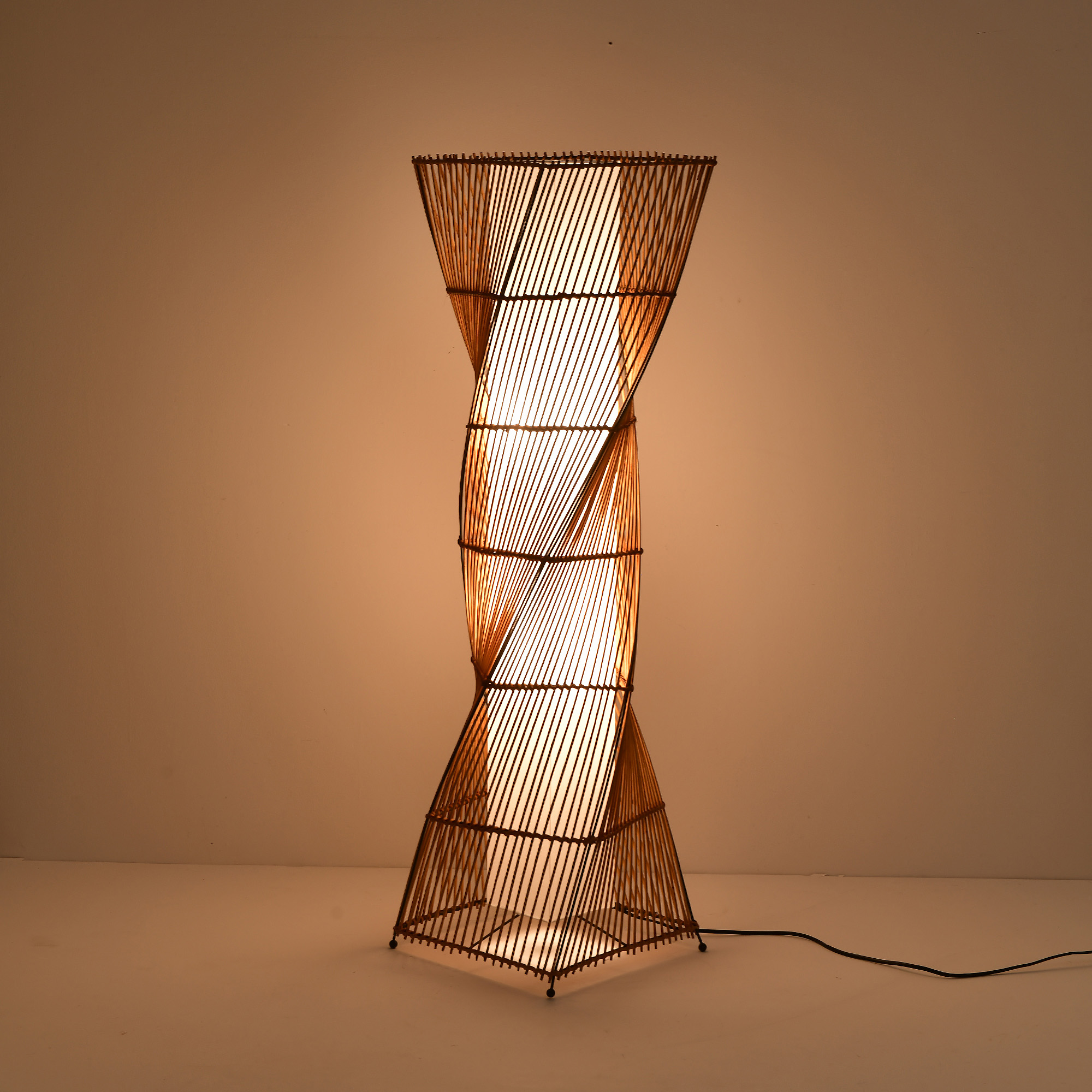 Eine Stehlampe im Bambus-Stil mit einem gewundenen Design, mit weißem Licht.