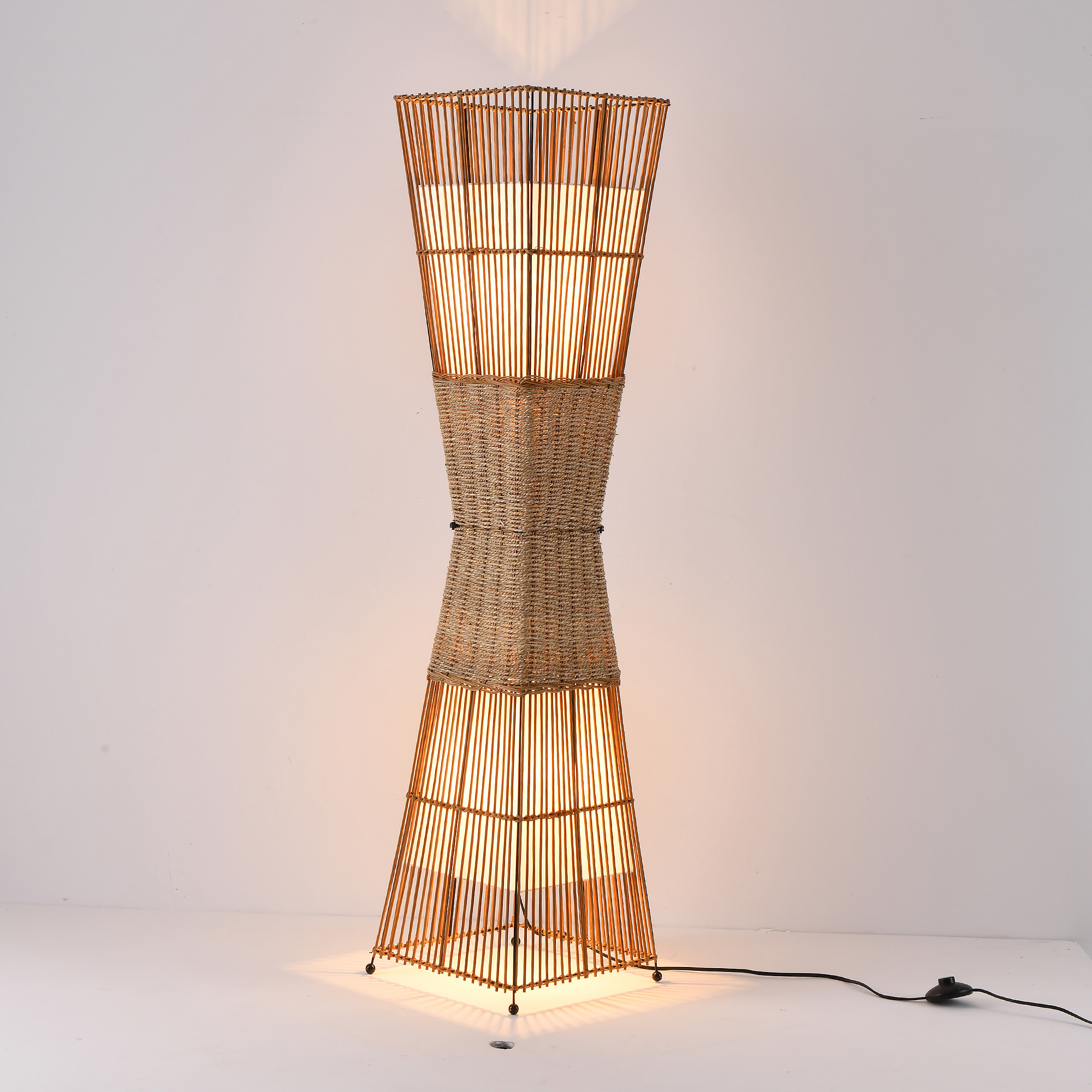 Eine hohe, dekorative Stehlampe mit gewebtem Design und warmer Beleuchtung.