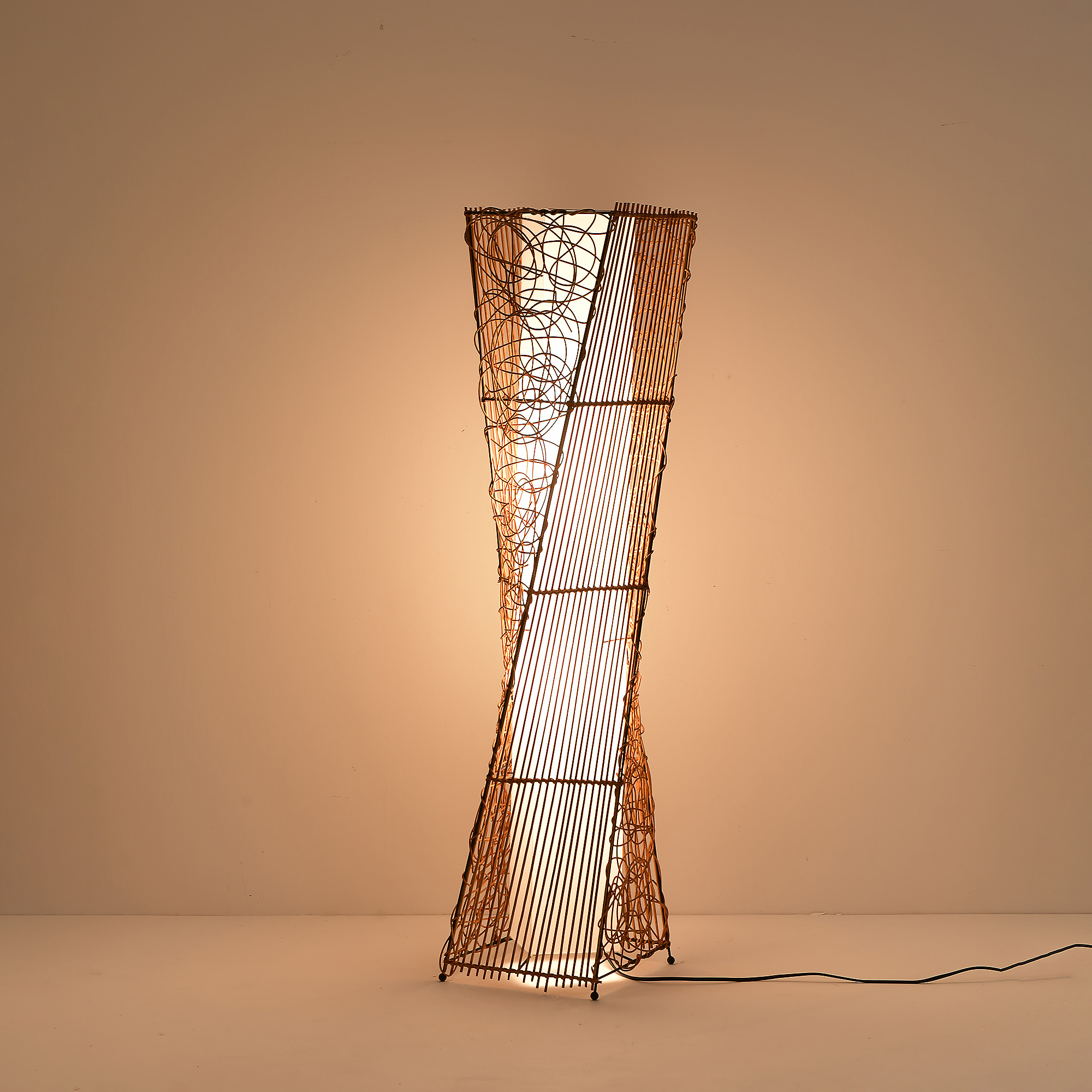 Eine hohe, gewebte Lampe mit Licht, vor einem hellen Hintergrund platziert.