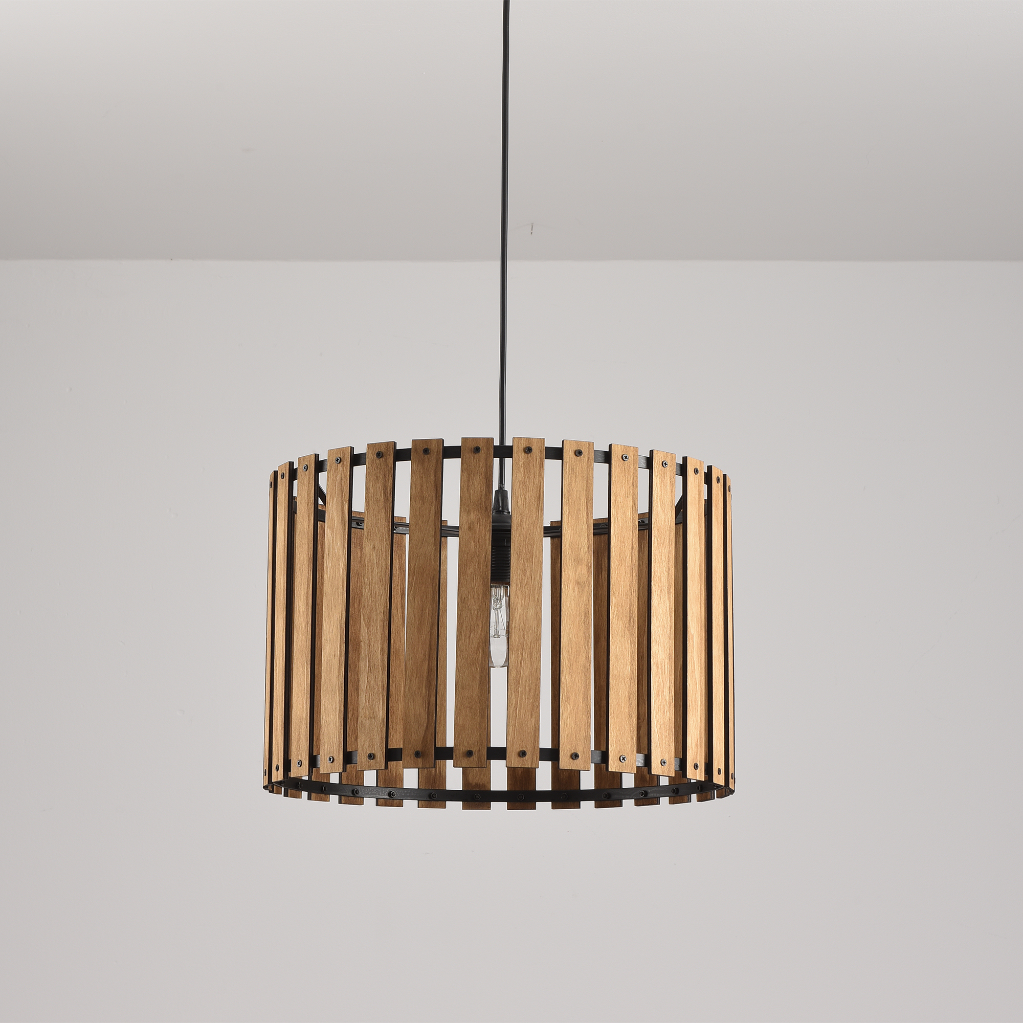 Eine zylindrische Holzlampe, die von der Decke hängt. Die Lampe besteht aus Holzlatten.
