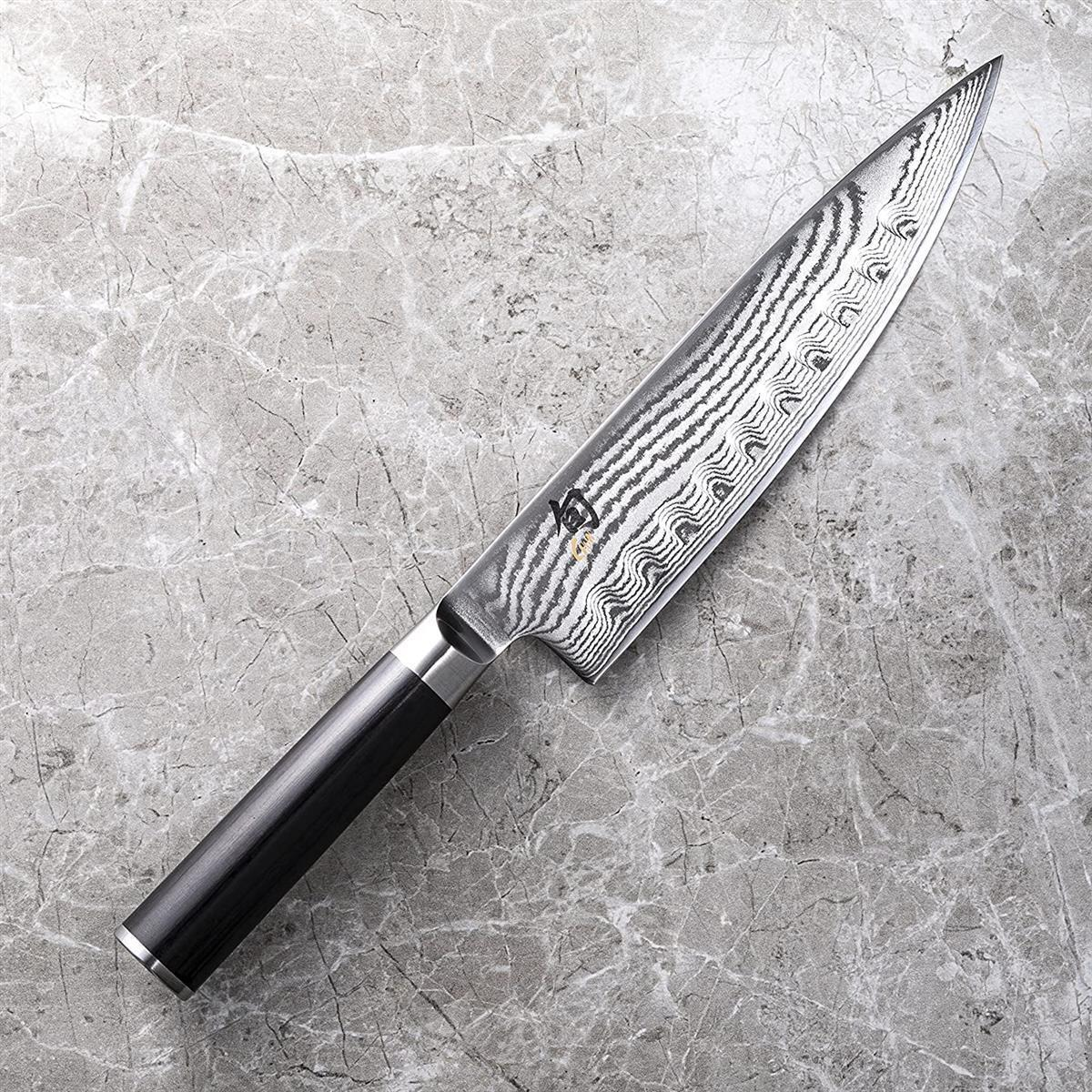 Coltello da chef giapponese su superficie in marmo con manico in legno.