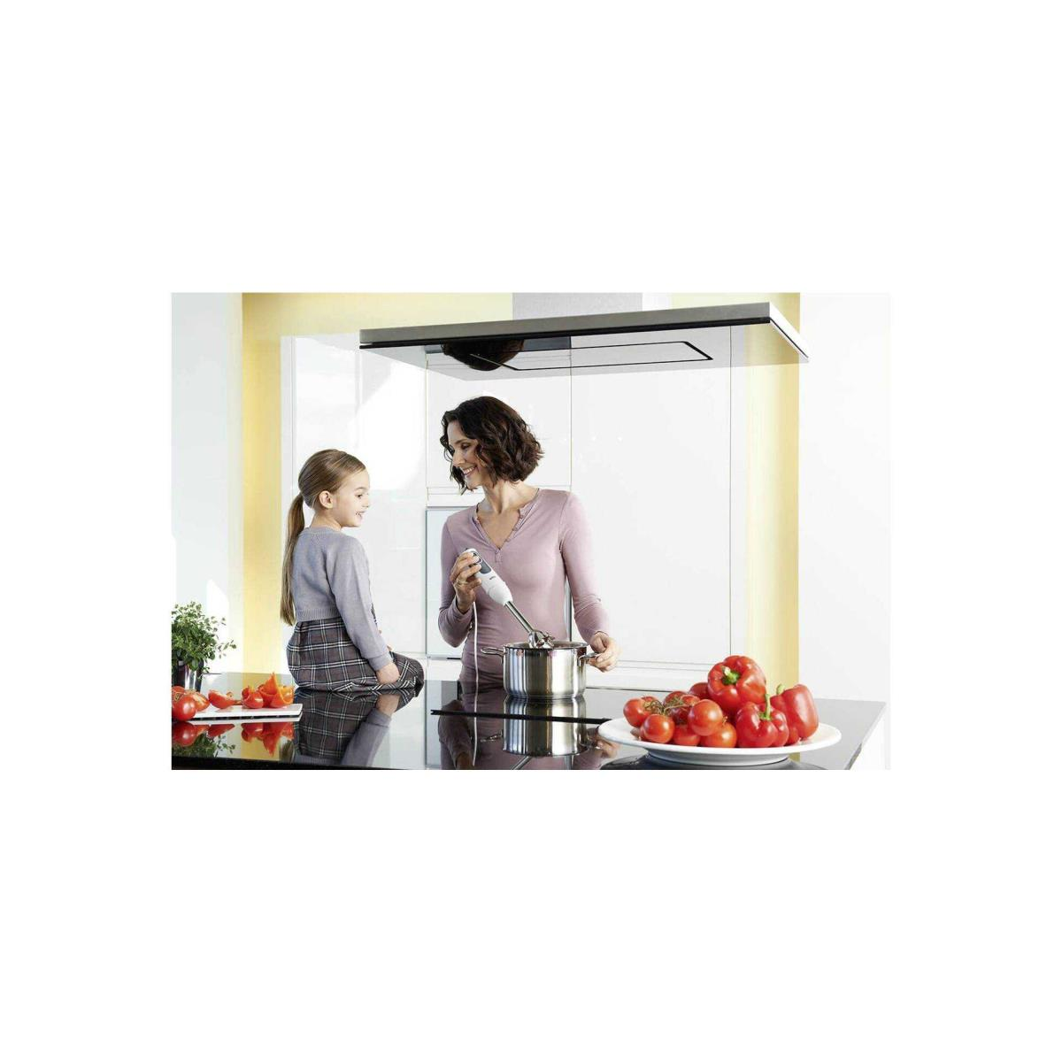Mujer y niña en cocina, mujer usando batidora de inmersión en olla.