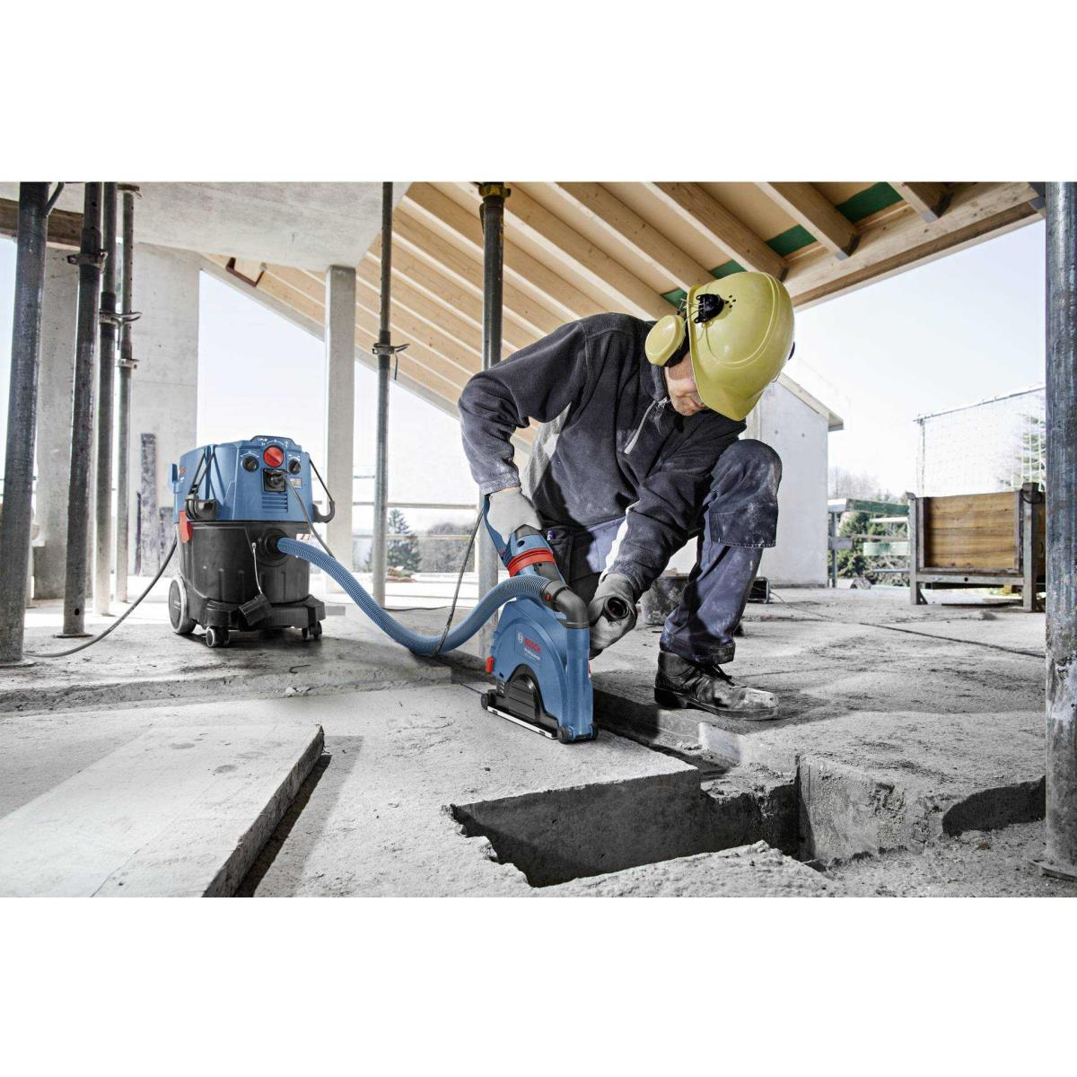 Un trabajador de la construcción usando una sierra de concreto con aspiradora en un sitio de construcción.