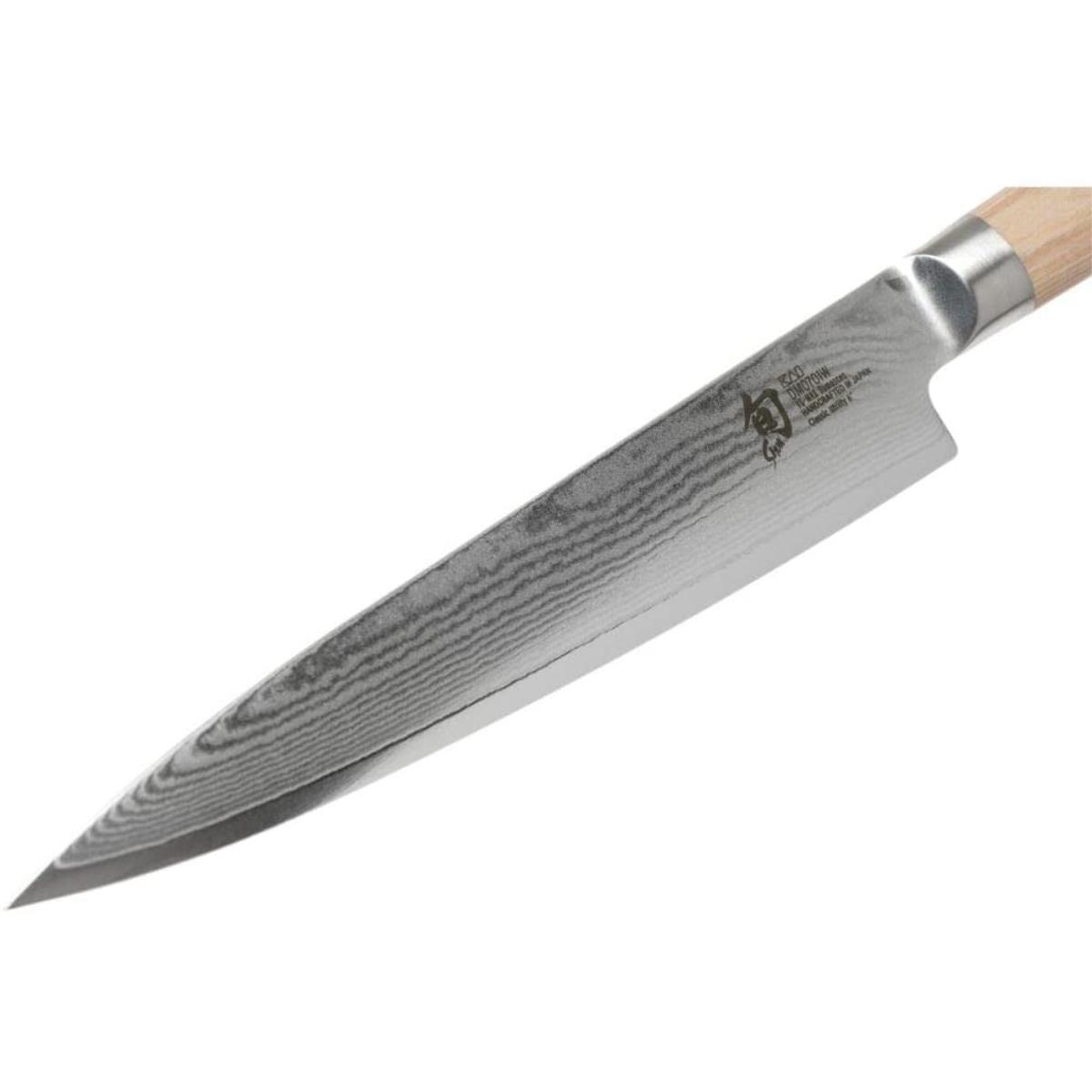 Szczegół ostrza noża Shun, srebrne ostrze, białe tło.