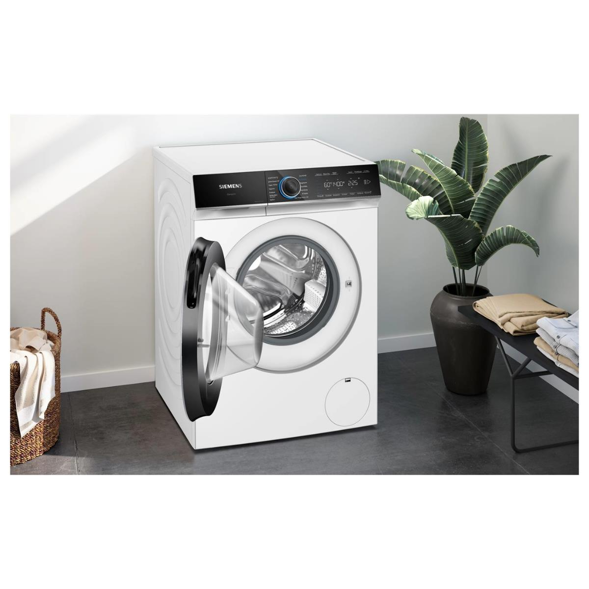 Biała pralka z otwartymi drzwiami, czarnymi akcentami i rośliną po prawej.