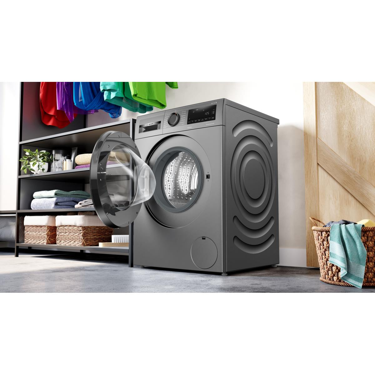 Wasmachine met open deur, wasmand en kleding, naast een kast.