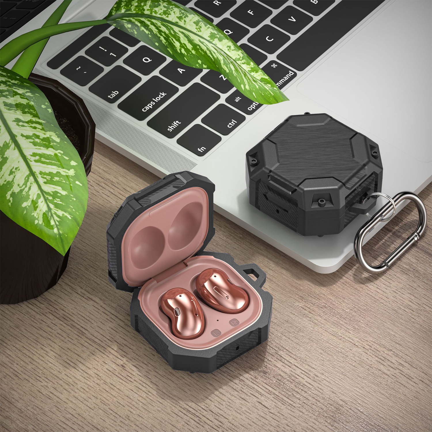 Kopfhörer in Schutzhülle neben Laptop und Pflanze.