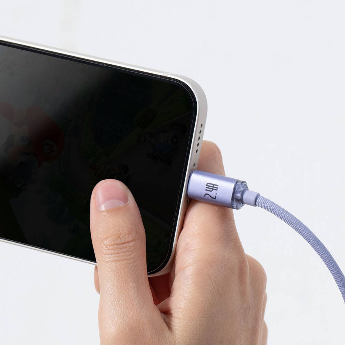 Dłoń trzymająca telefon z podłączonym kablem ładującym; kabel jest lawendowy.