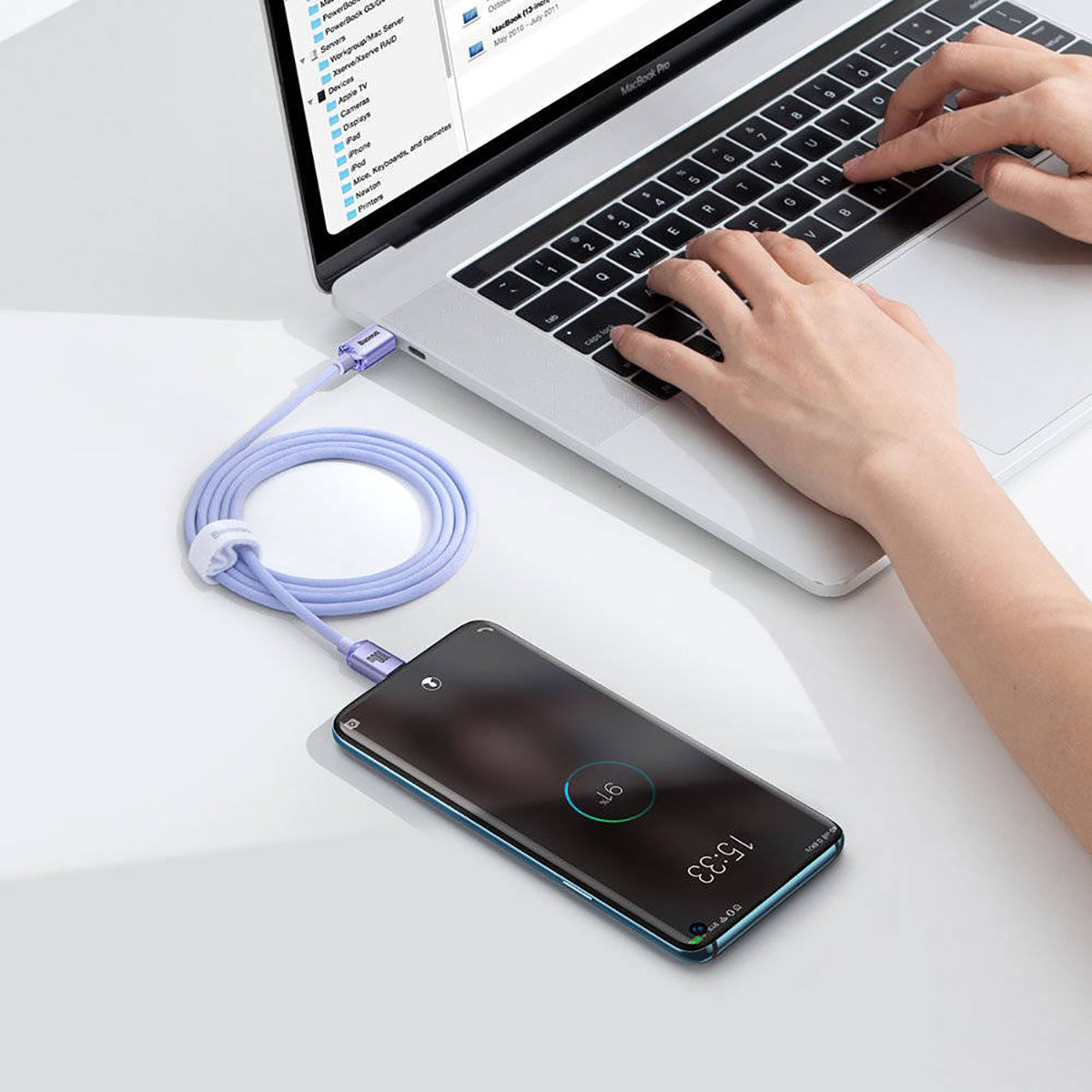 Telefono in carica con cavo viola, collegato a un laptop.
