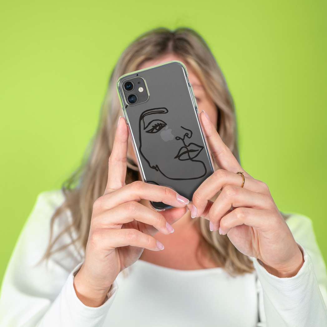 Donna che tiene un telefono con un design a contorno facciale su sfondo verde.