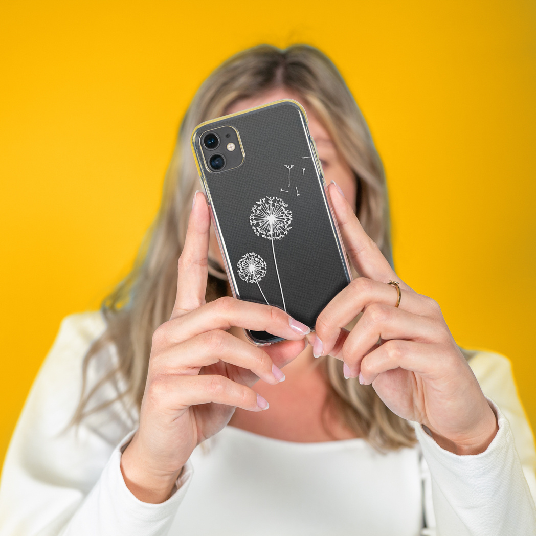 Una persona che tiene in mano un telefono con un design di dente di leone bianco su sfondo giallo.