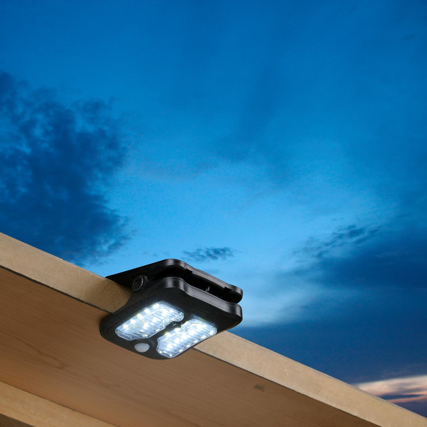 Black solar light on wooden surface against a cloudy sky.