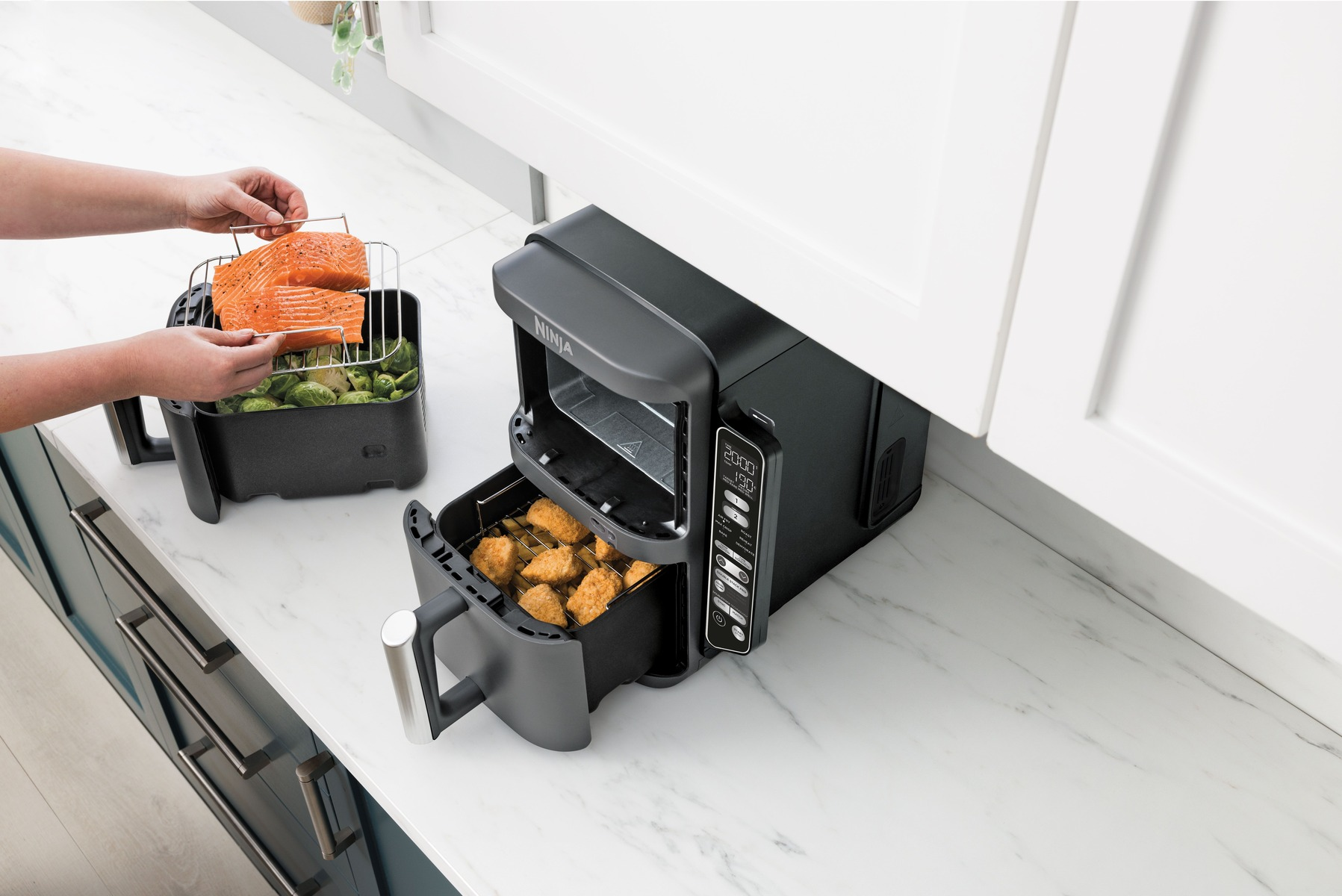 Scena kuchenna z frytownicą powietrzną Ninja i łososiem umieszczanym wewnątrz frytownicy.