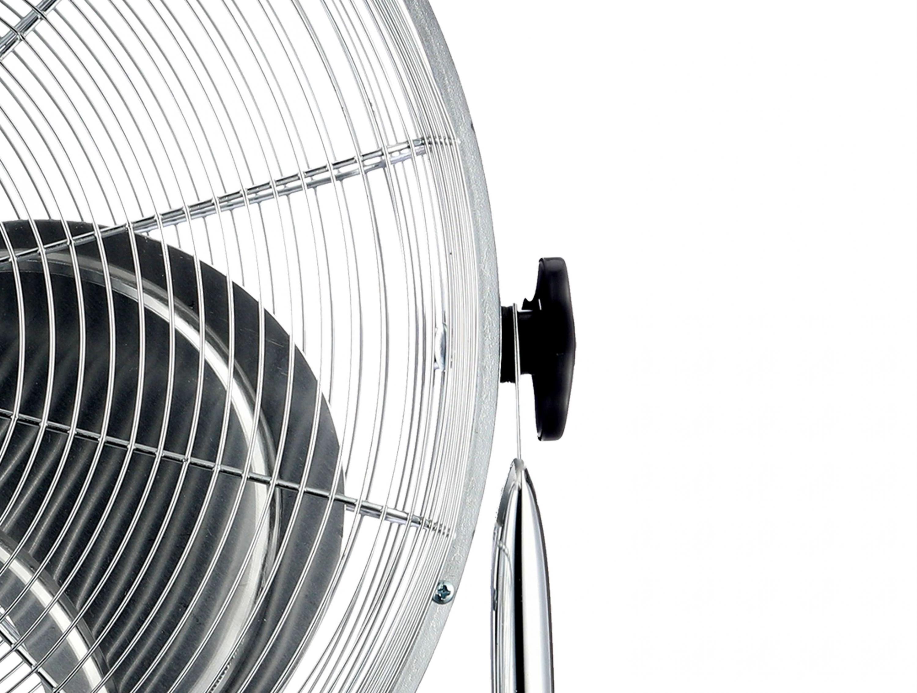 Primer plano de un ventilador plateado con perilla negra. El fondo es blanco.