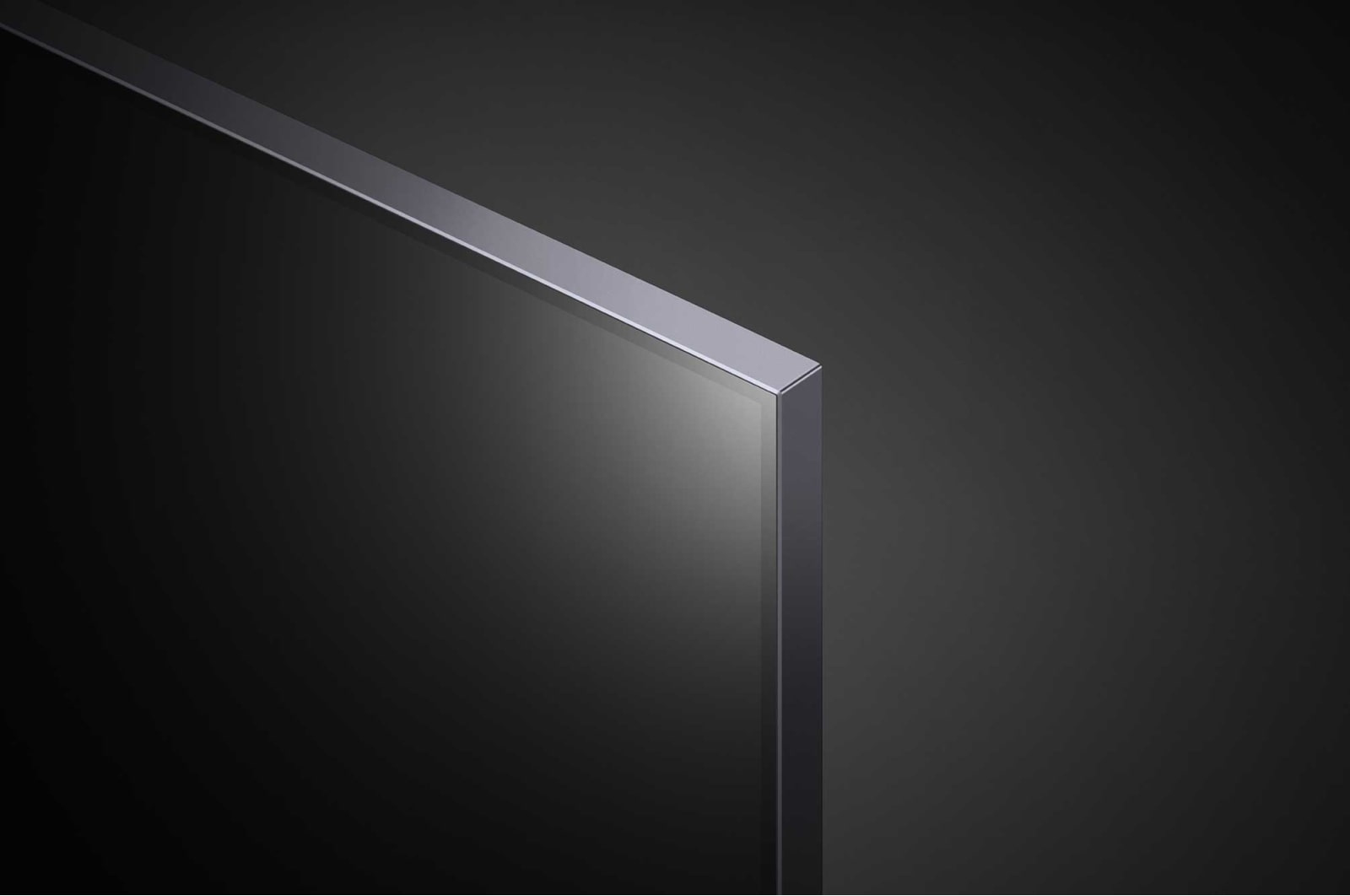 Narożnik dużego, czarnego telewizora z srebrną ramką. Ciemne tło.