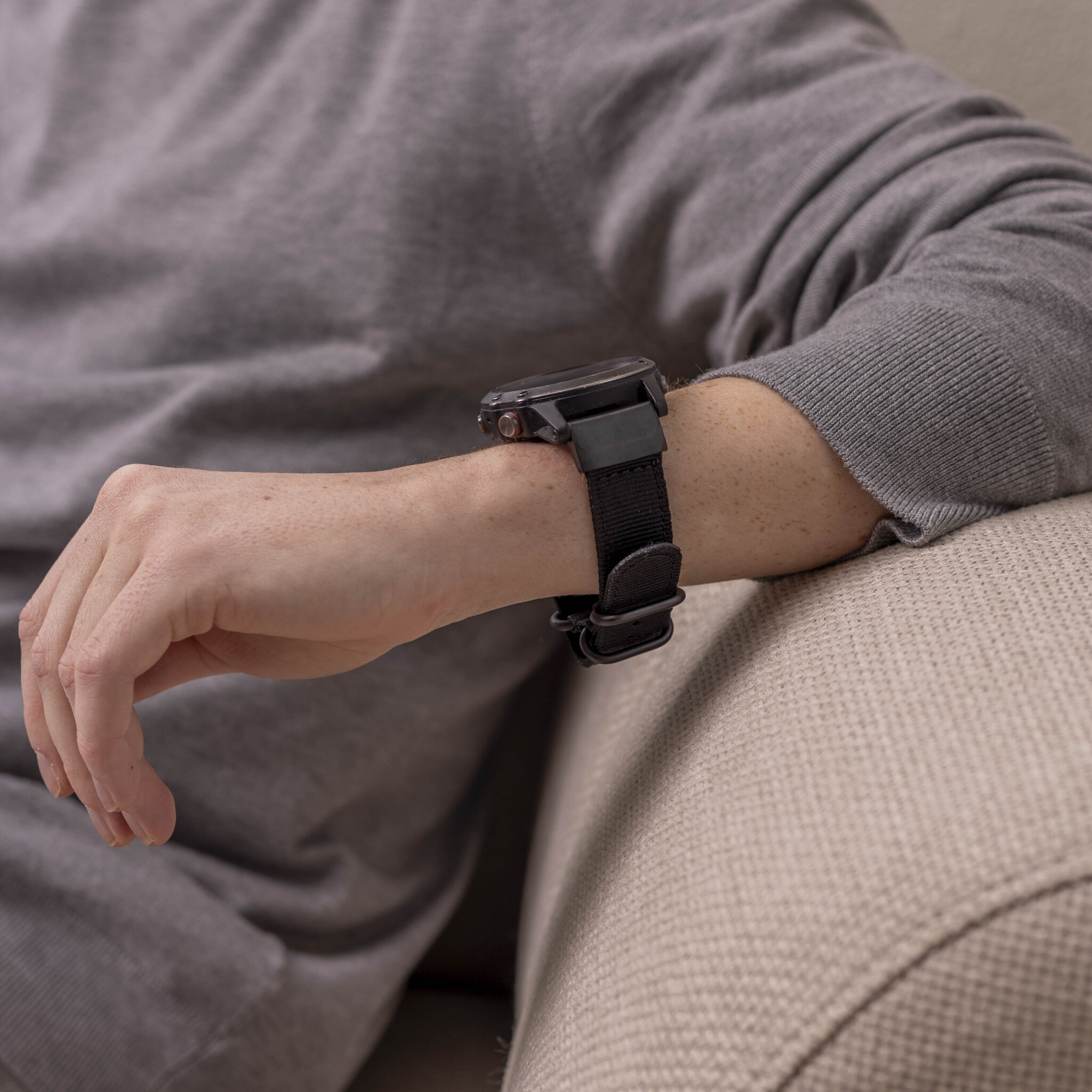 Nahaufnahme eines Handgelenks mit einer schwarzen Uhr und einem schwarzen Armband.