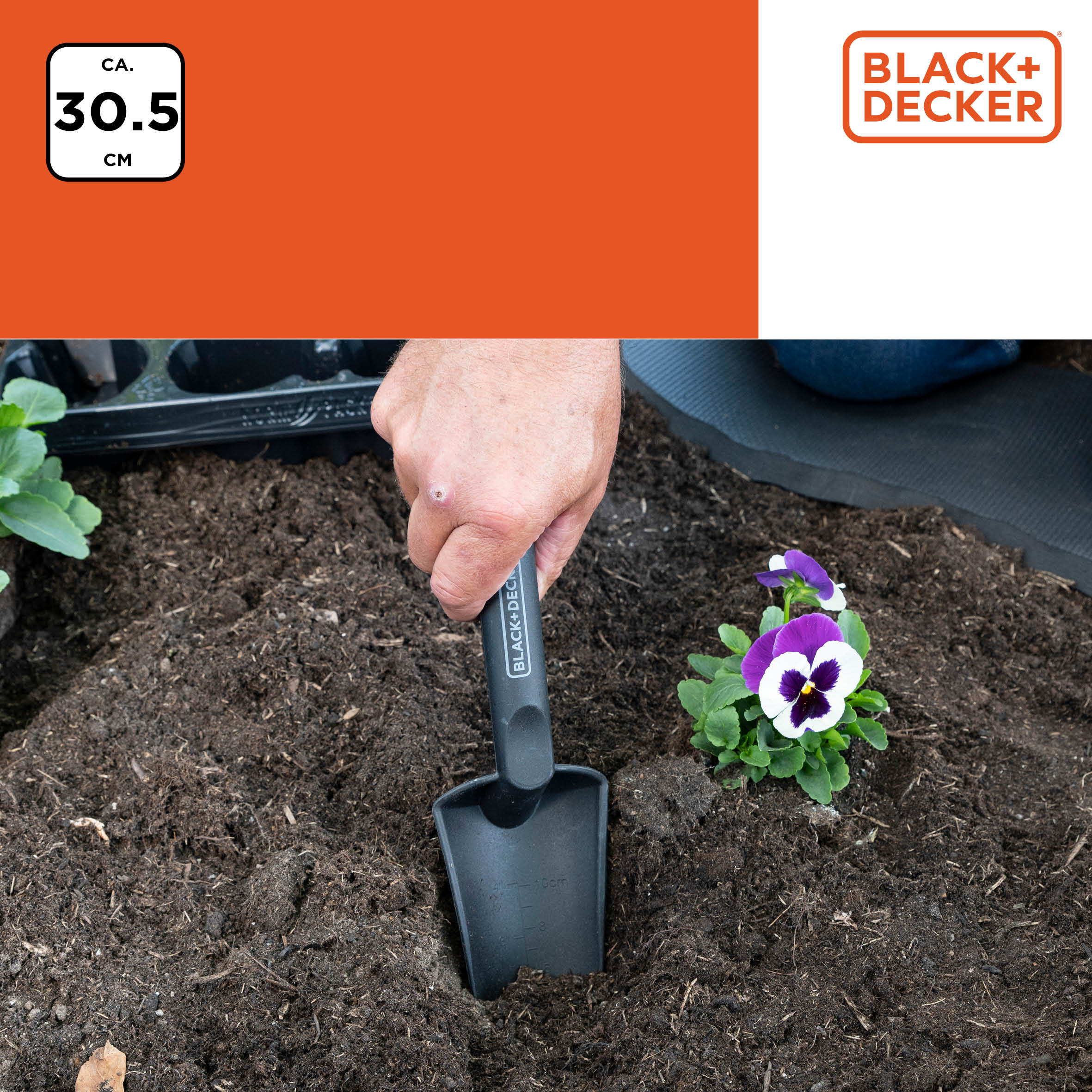 Hand planting with a small black shovel into soil. A flower and the Black+Decker logo are shown.