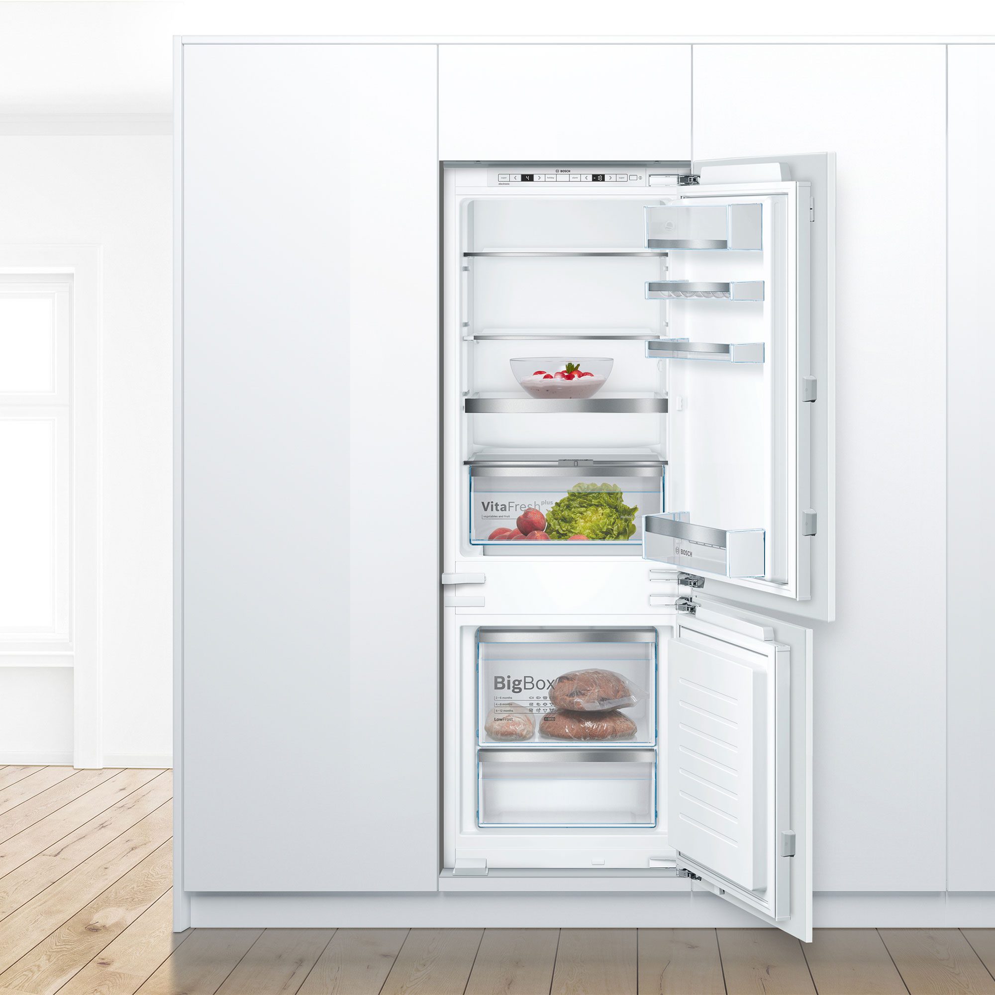 Frigorifero bianco ad incasso con ante aperte. L'interno ha ripiani, cassetti e generi alimentari.