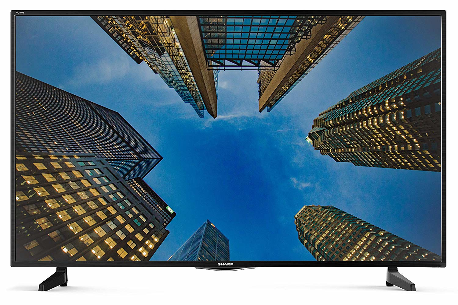 Un televisore Sharp mostra una vista dal basso di edifici alti contro un cielo blu.