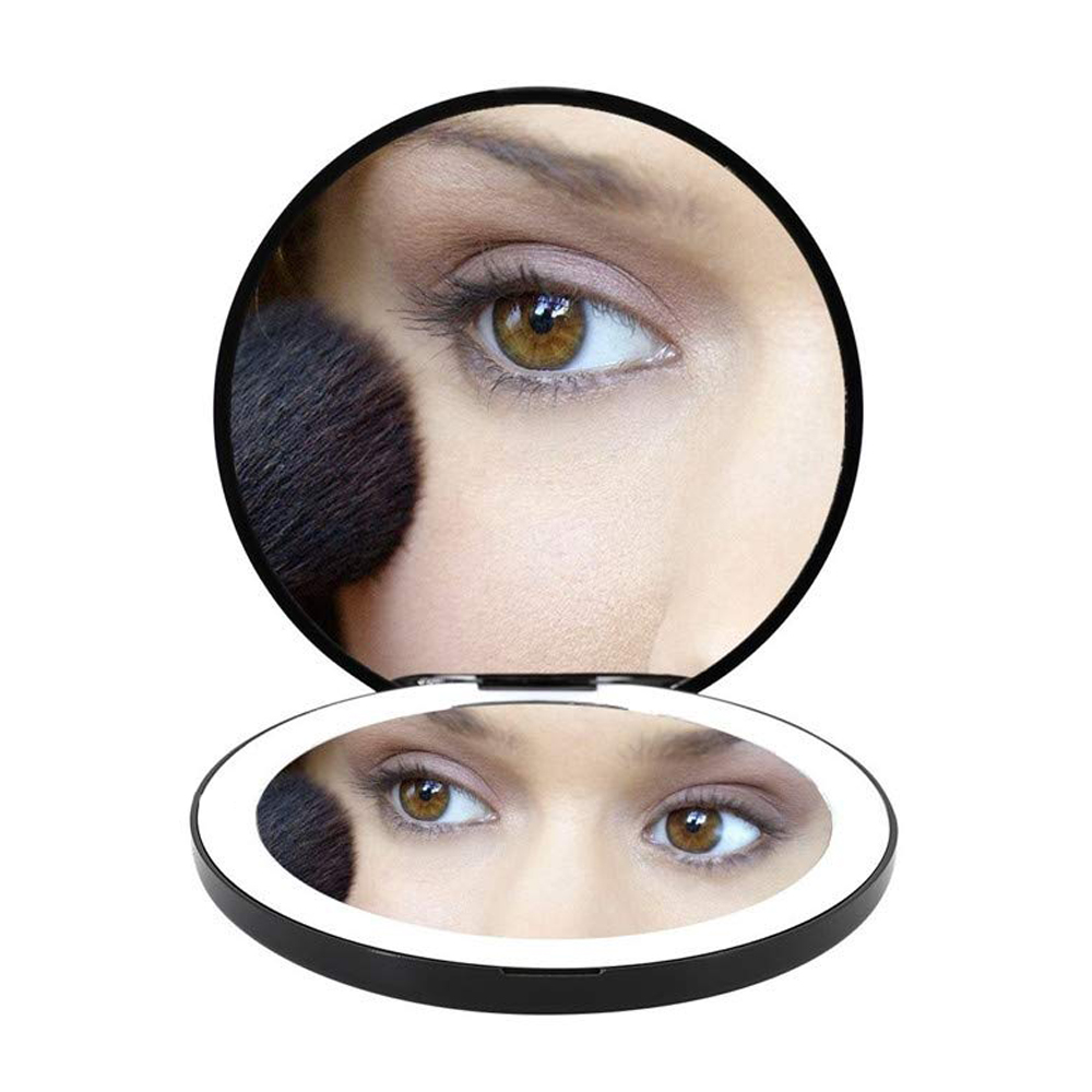 Auge einer Frau in einem runden Spiegel. Make-up-Pinsel nahe ihrem Gesicht.