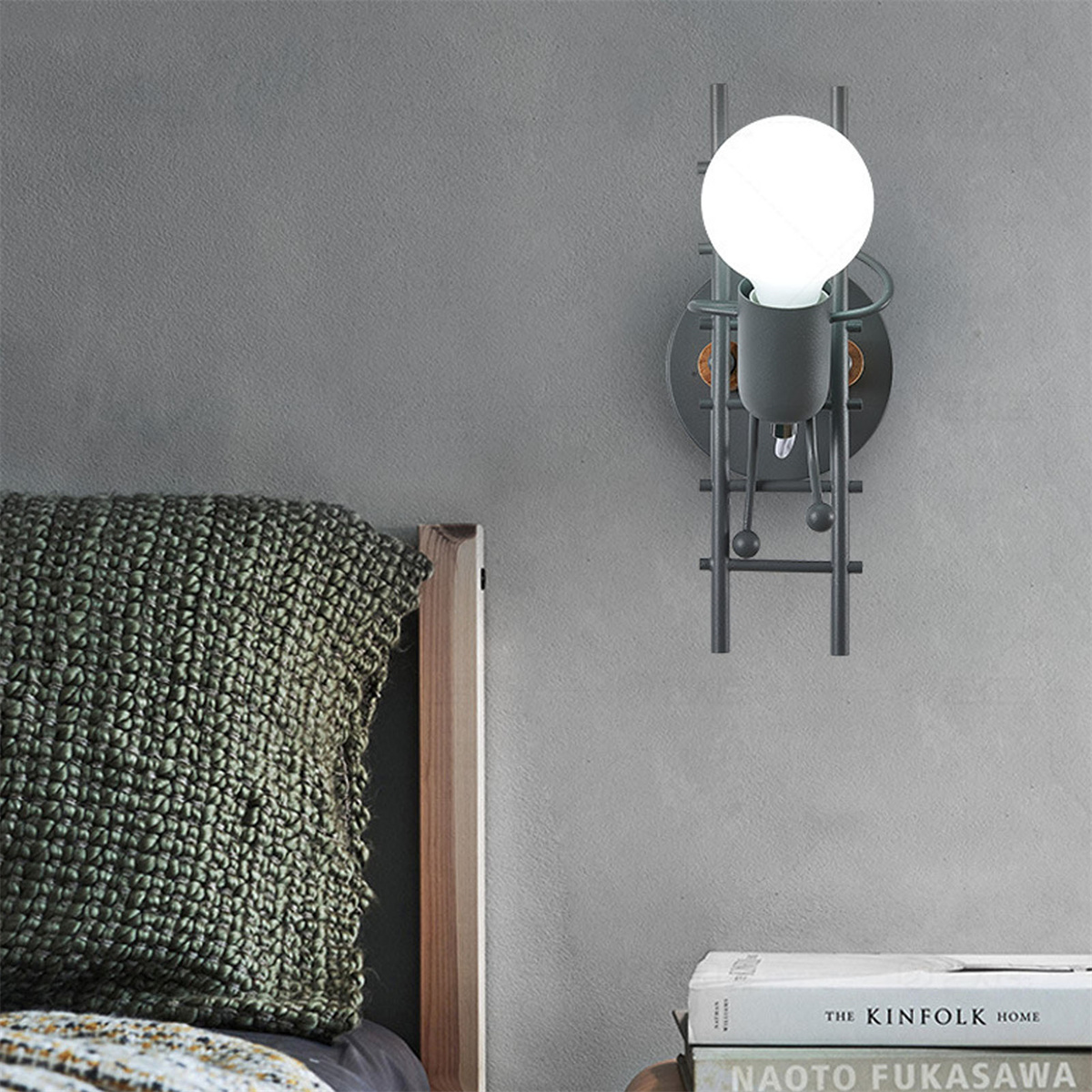 Eine Wandlampe in Form einer Person, die eine Leiter neben einem Bett hochsteigt.